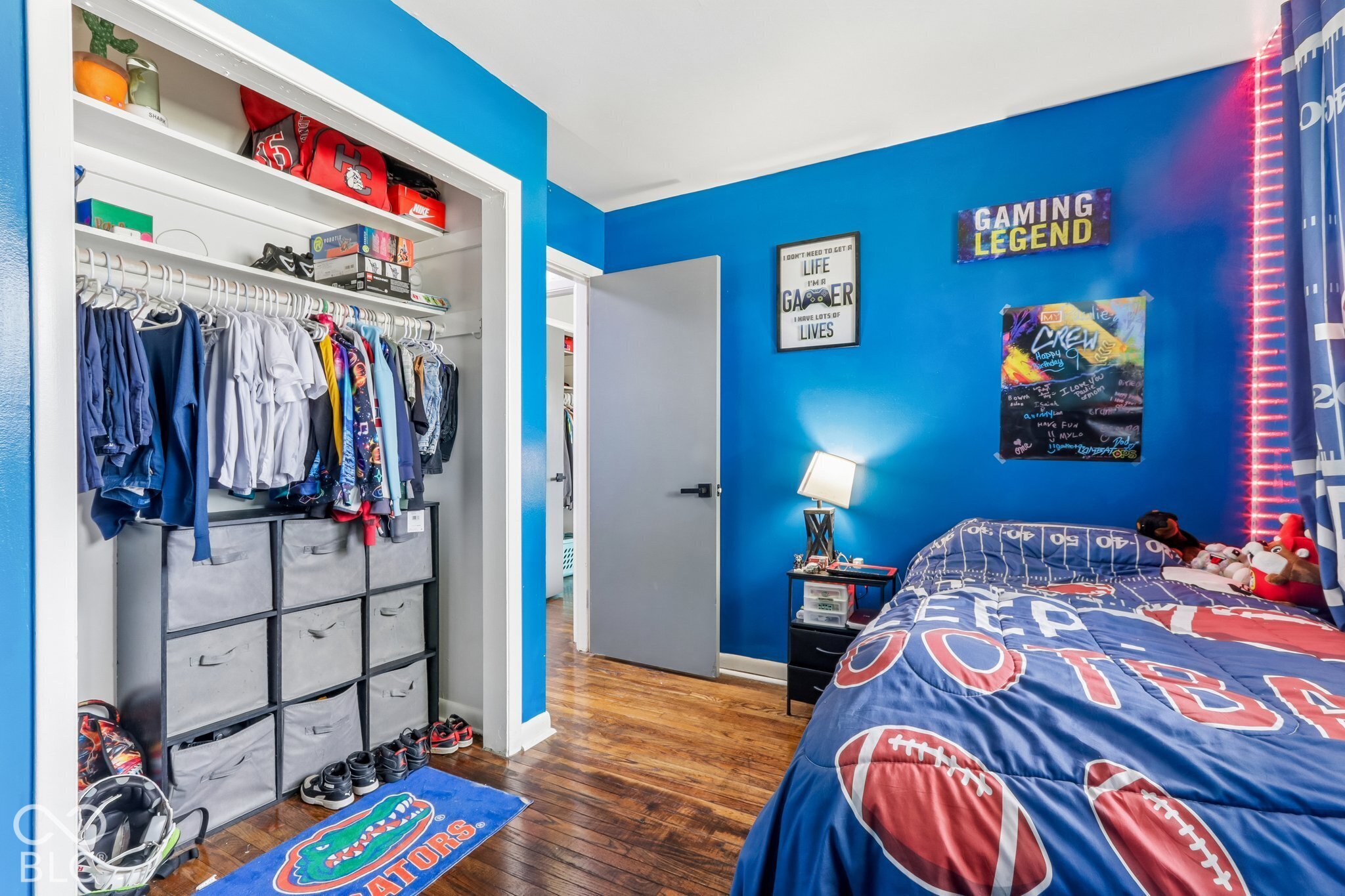 Bedroom featuring wood-finish flooring, a built-in closet with overhead shelving, and a solid-core interior door with matte black hardware