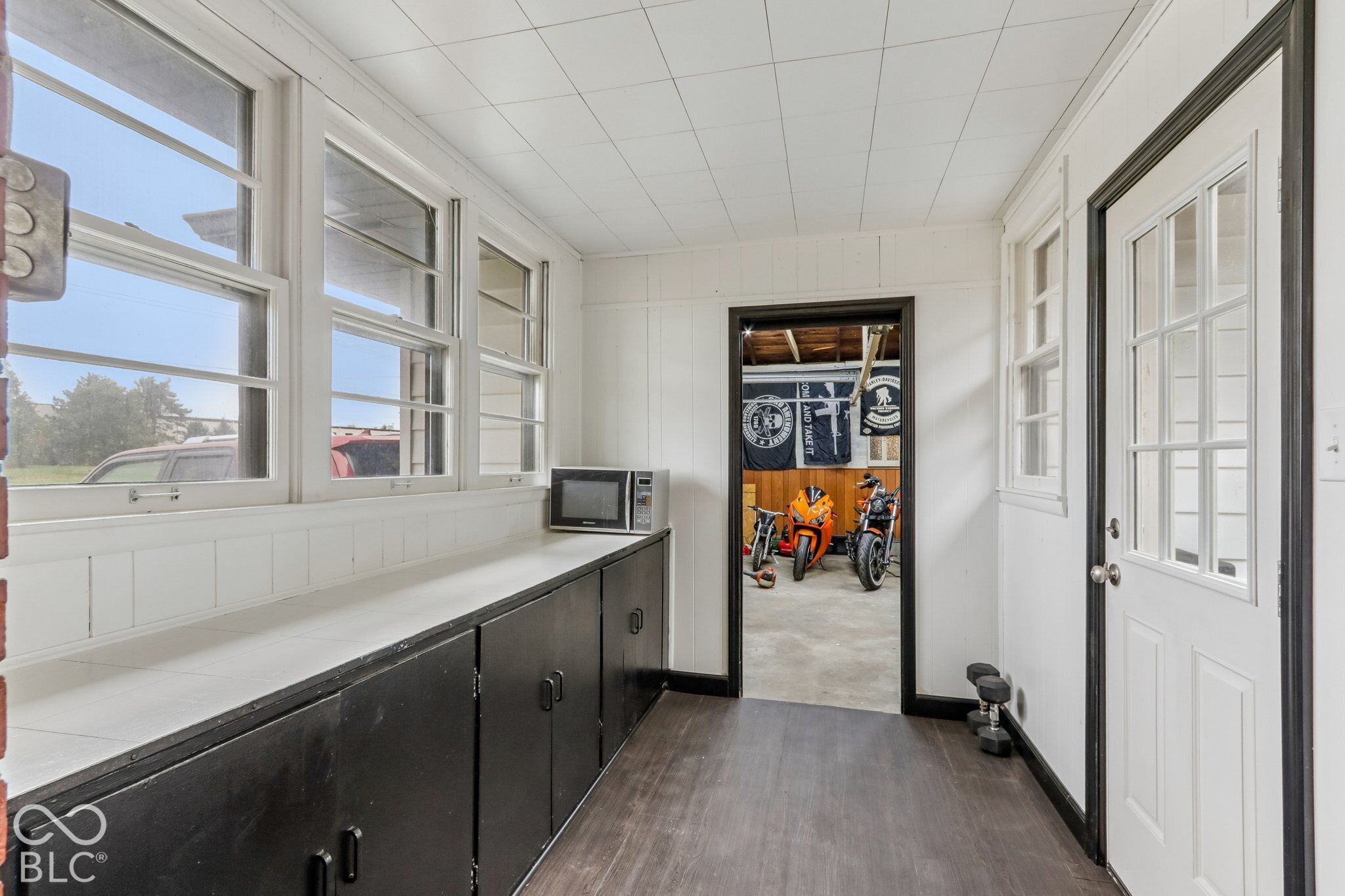 Enclosed porch featuring wood-finish flooring, extensive built-in cabinetry with white countertops, and multiple windows