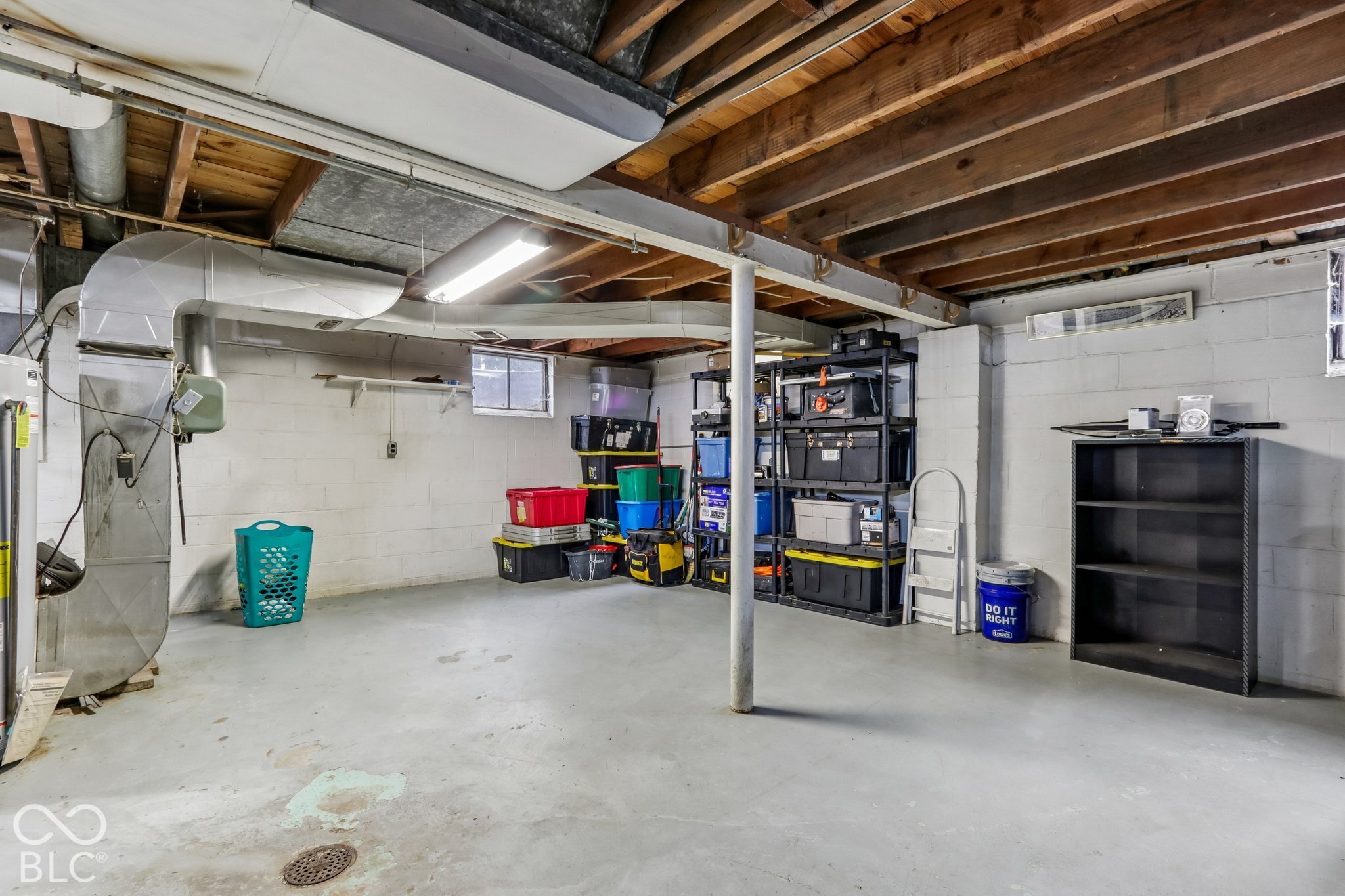Unfinished lower level featuring exposed wood joist ceilings, painted concrete block walls, and a painted concrete floor