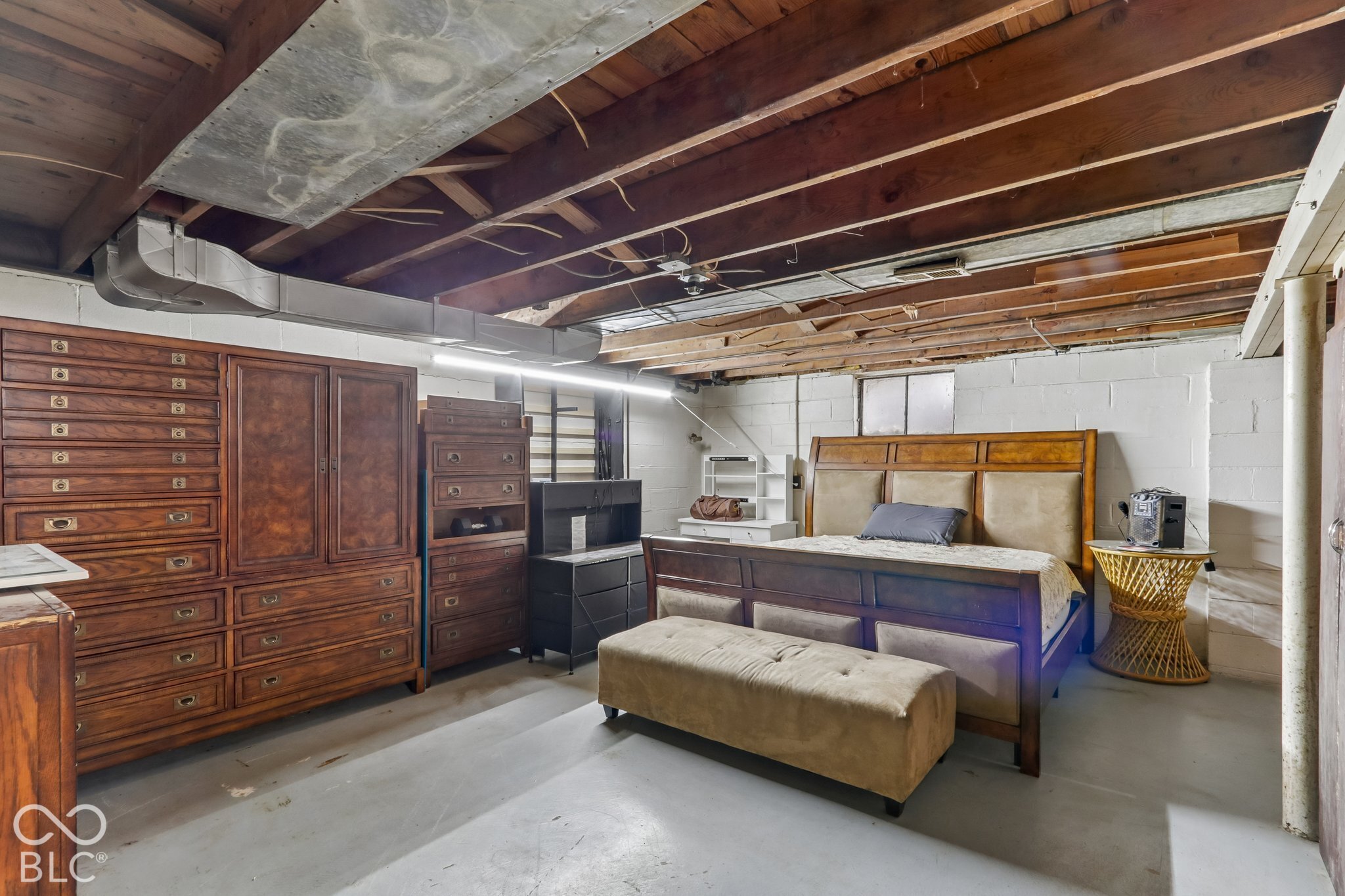 Unfinished space featuring exposed timber joist ceiling, painted masonry walls, concrete flooring, and metal ductwork