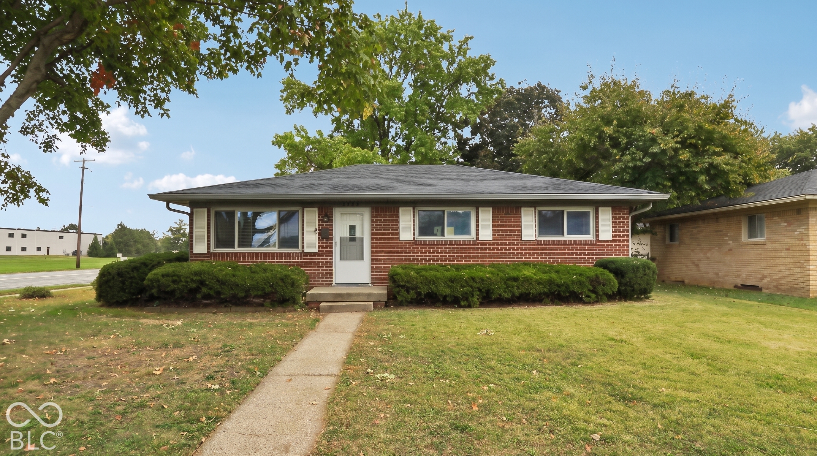 Single-story brick exterior featuring a hip roof, horizontal sliding windows with white shutters, and a central entryway with a concrete stoop
