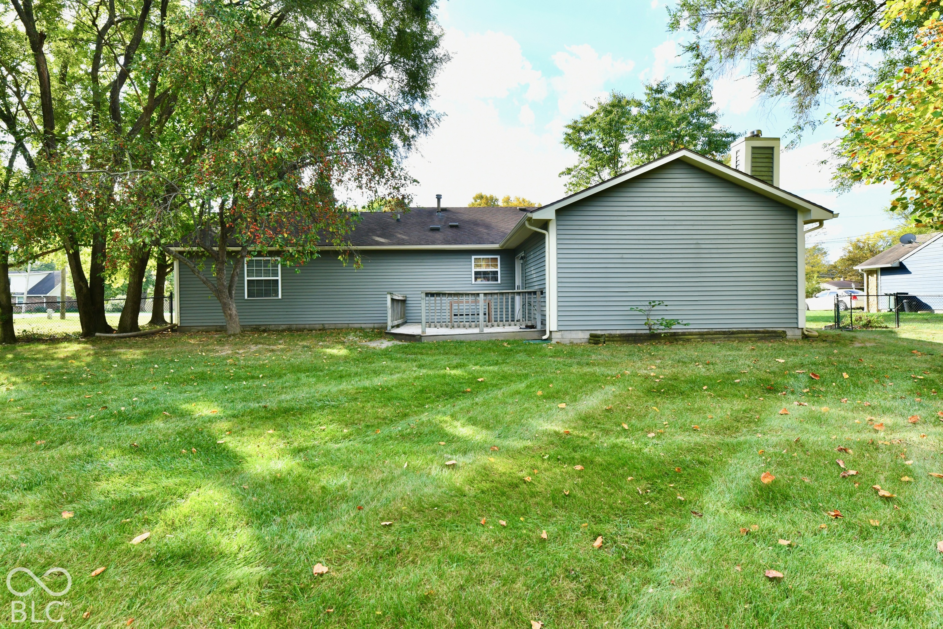 Backyard featuring horizontal siding, a wooden deck, and mature trees