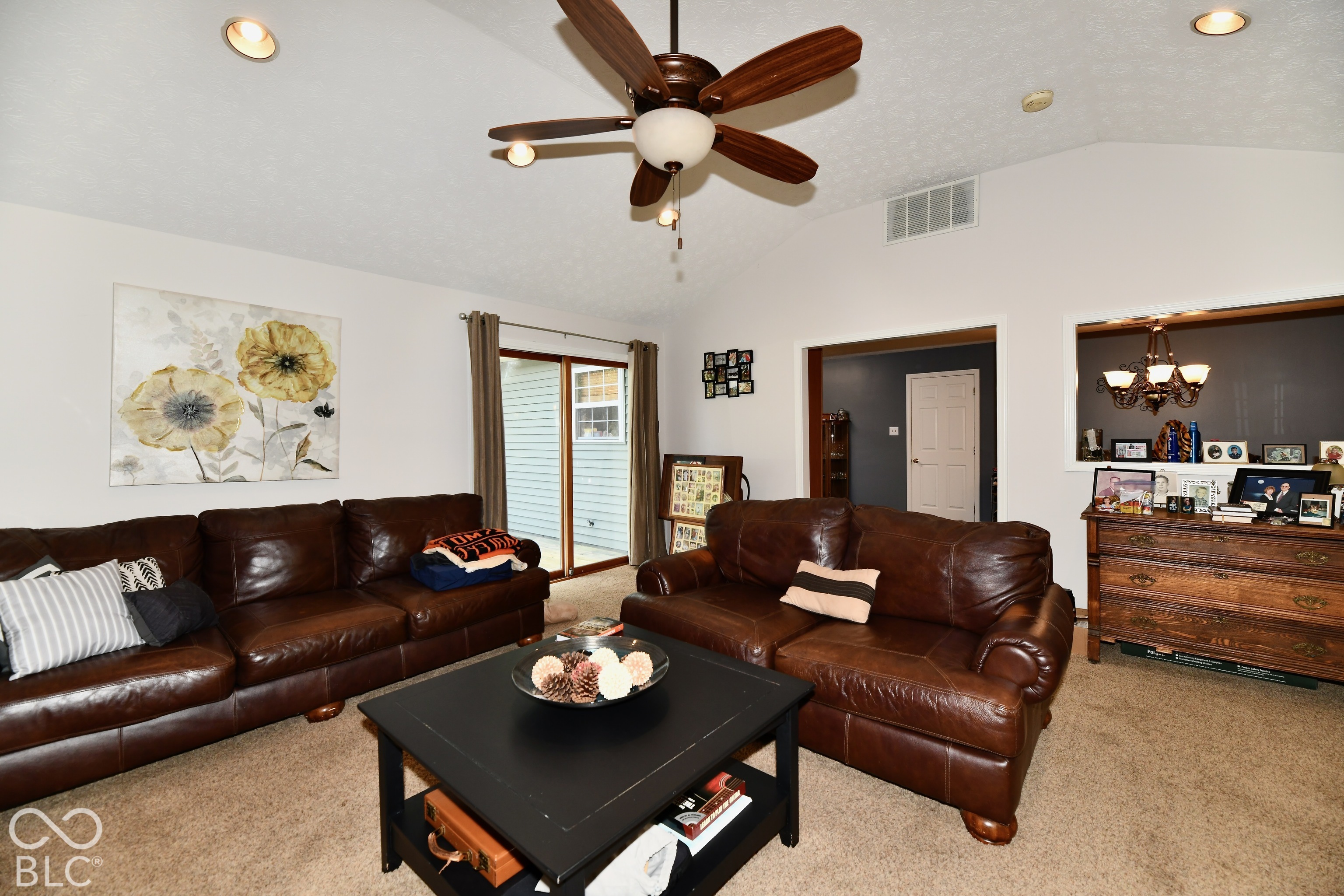 Vaulted ceiling, multi-blade ceiling fan with integrated light fixture, and sliding glass door