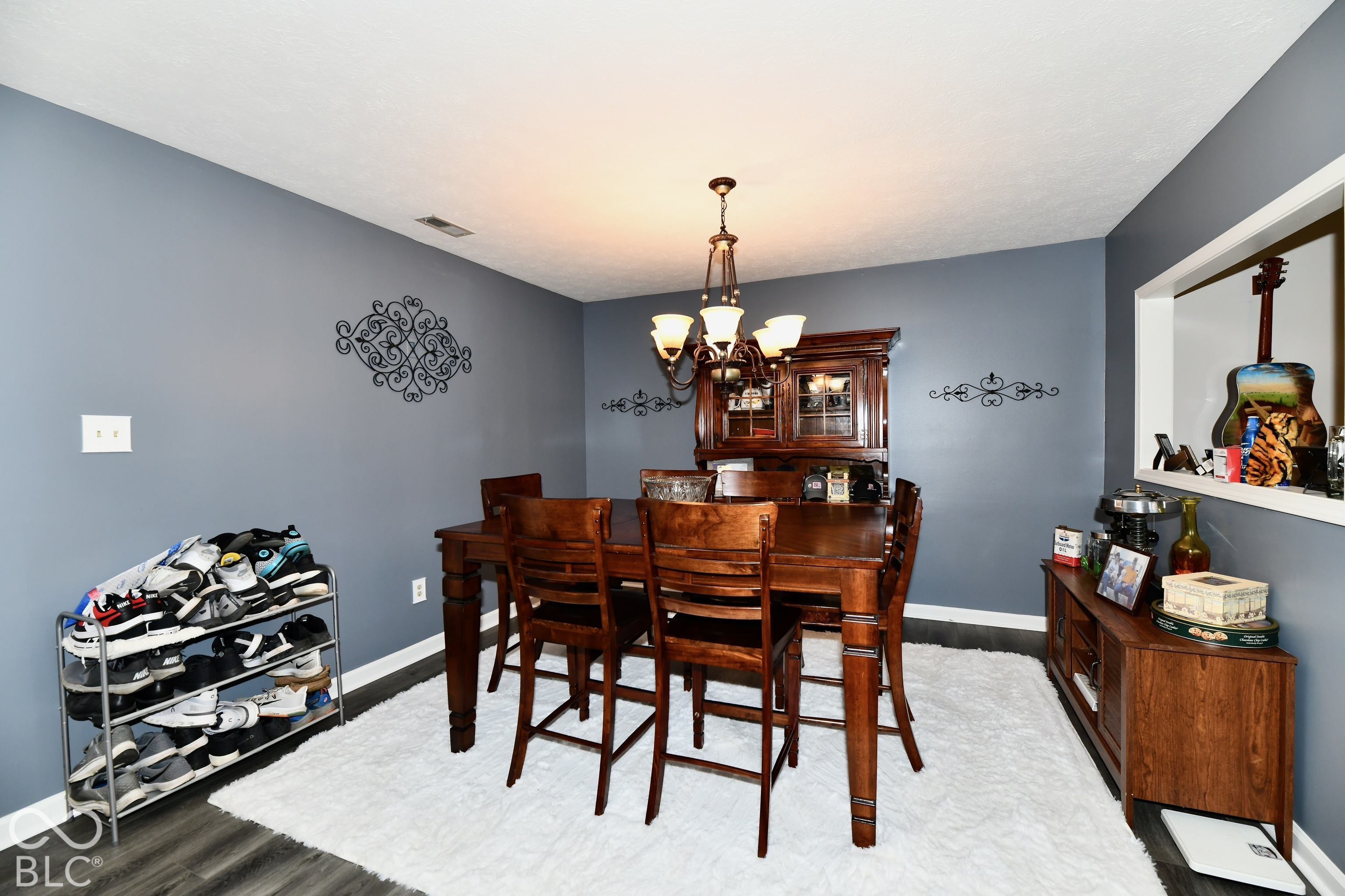 Dining area featuring wood-finish flooring, a multi-light chandelier, and a pass-through wall opening