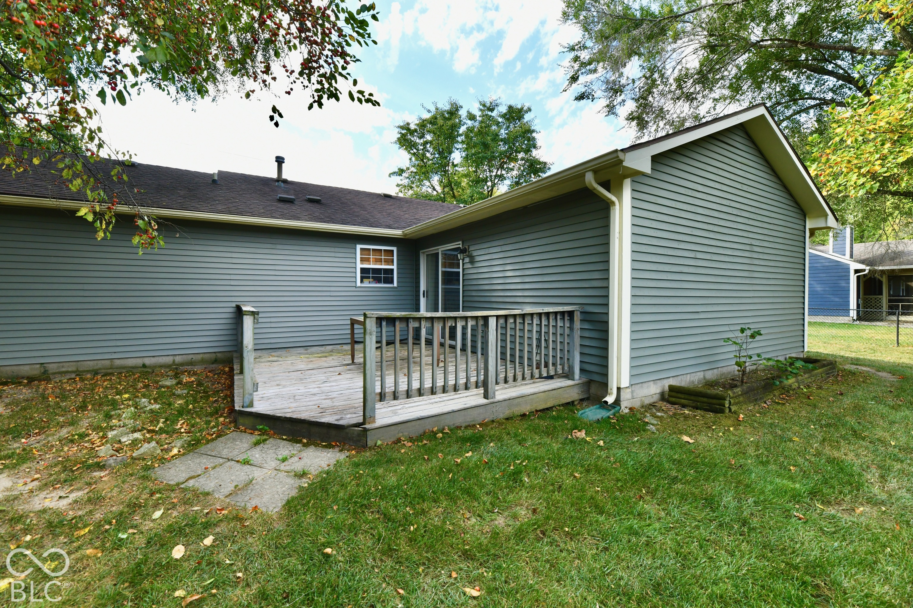 Exterior featuring horizontal siding, a raised wooden deck with railings, and a concrete paver walkway