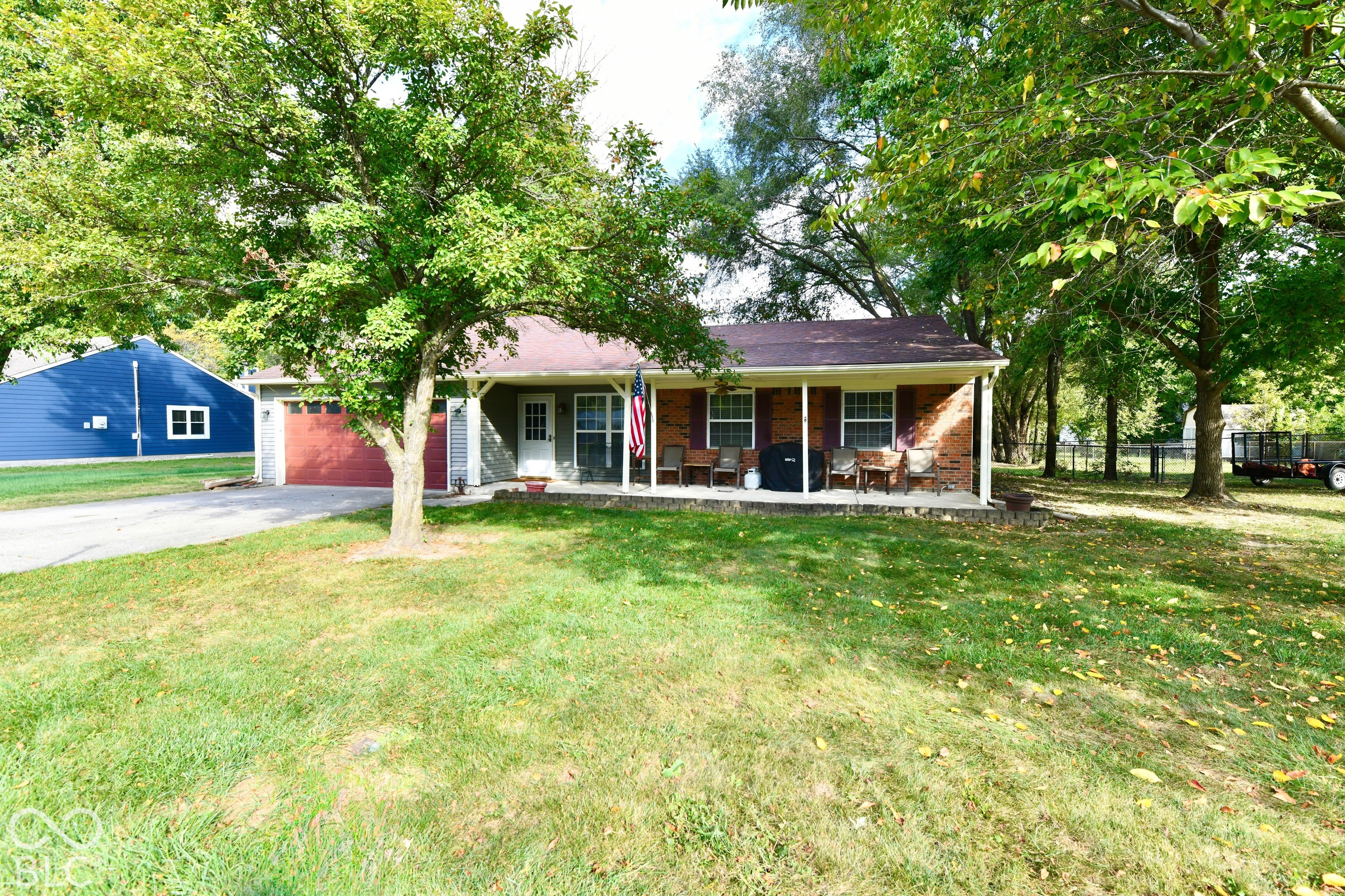Single-story residence featuring a brick and siding exterior, covered front porch, attached garage, and mature trees situated on a lawn Single-story residence featuring a brick and siding exterior, covered front porch, attached garage, and mature trees situated on a lawn