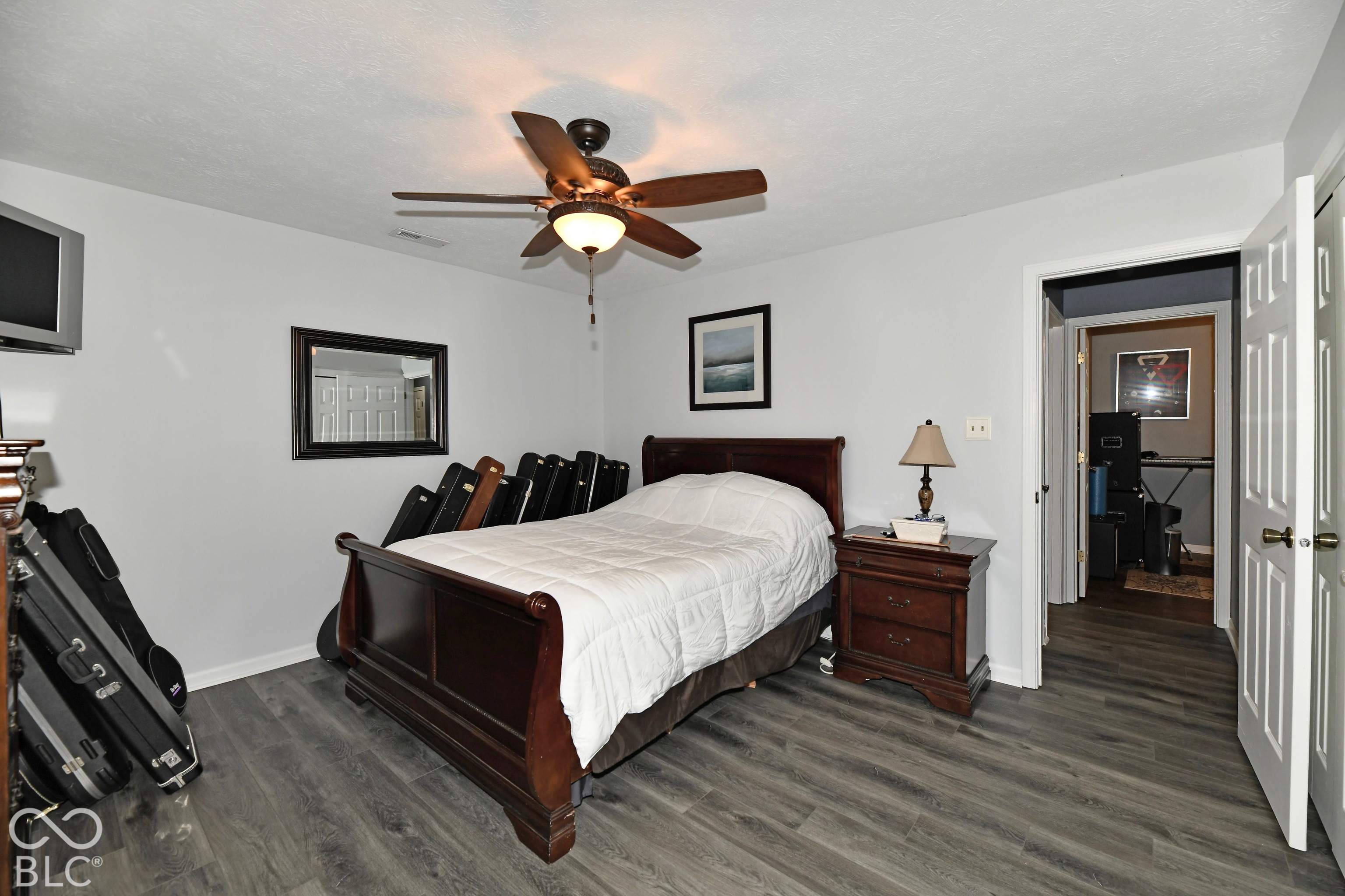 Room featuring wood-finish flooring, a ceiling fan with integrated lighting, and a six-panel door