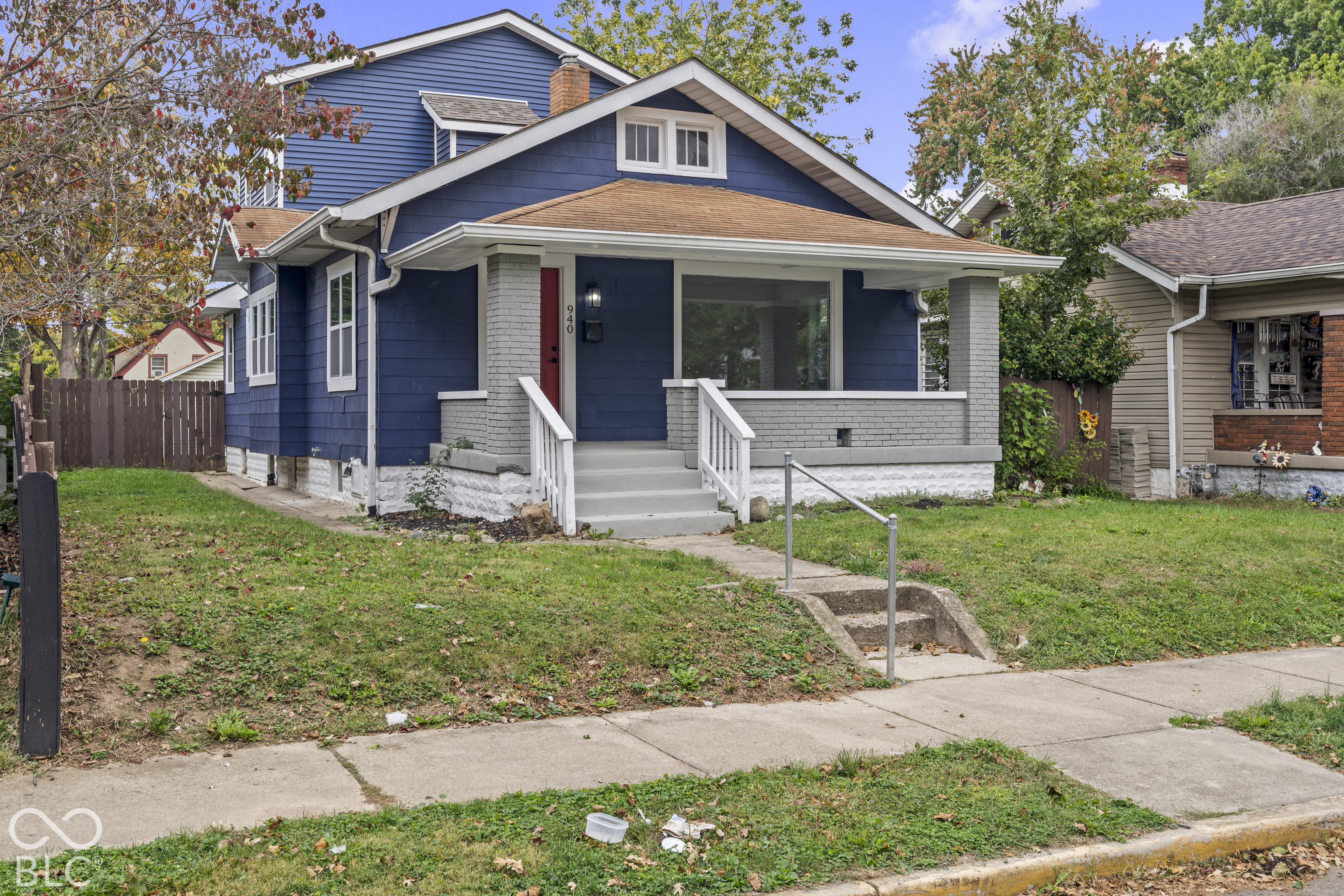 Craftsman-style exterior featuring blue shake siding, a covered front porch with masonry pillars, a gabled roofline, and a concrete walkway Craftsman-style exterior featuring blue shake siding, a covered front porch with masonry pillars, a gabled roofline, and a concrete walkway
