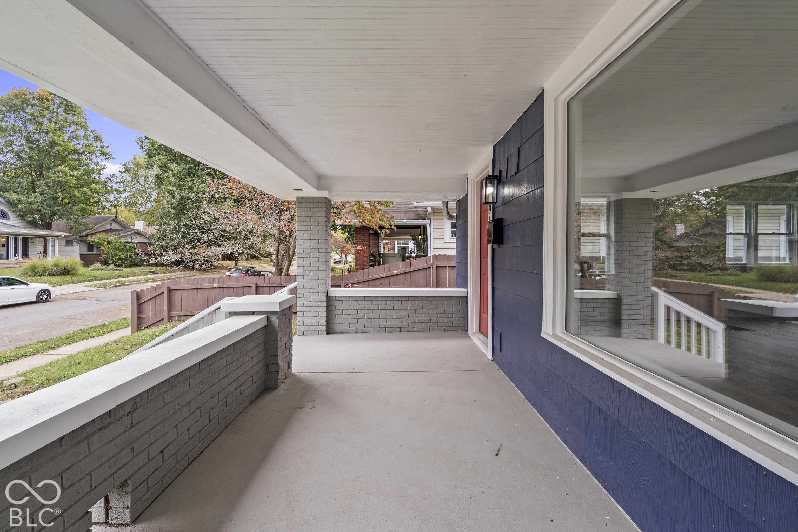 Covered porch featuring painted brick half-walls, concrete flooring, shake-style exterior siding, and a large picture window Covered porch featuring painted brick half-walls, concrete flooring, shake-style exterior siding, and a large picture window
