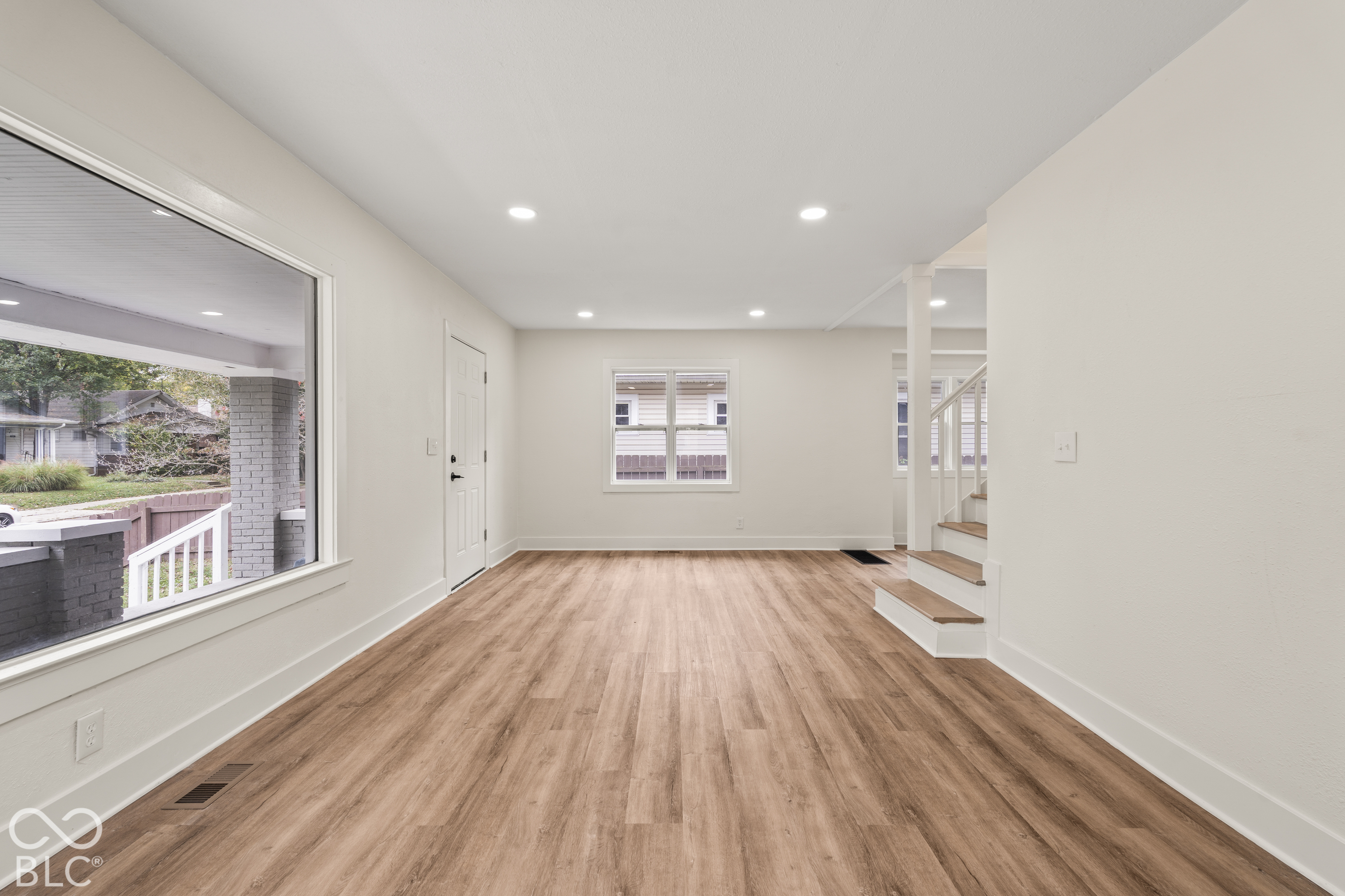 Interior space featuring wood-finish flooring, recessed lighting, expansive picture window, and stairs with wood-finish treads Interior space featuring wood-finish flooring, recessed lighting, expansive picture window, and stairs with wood-finish treads