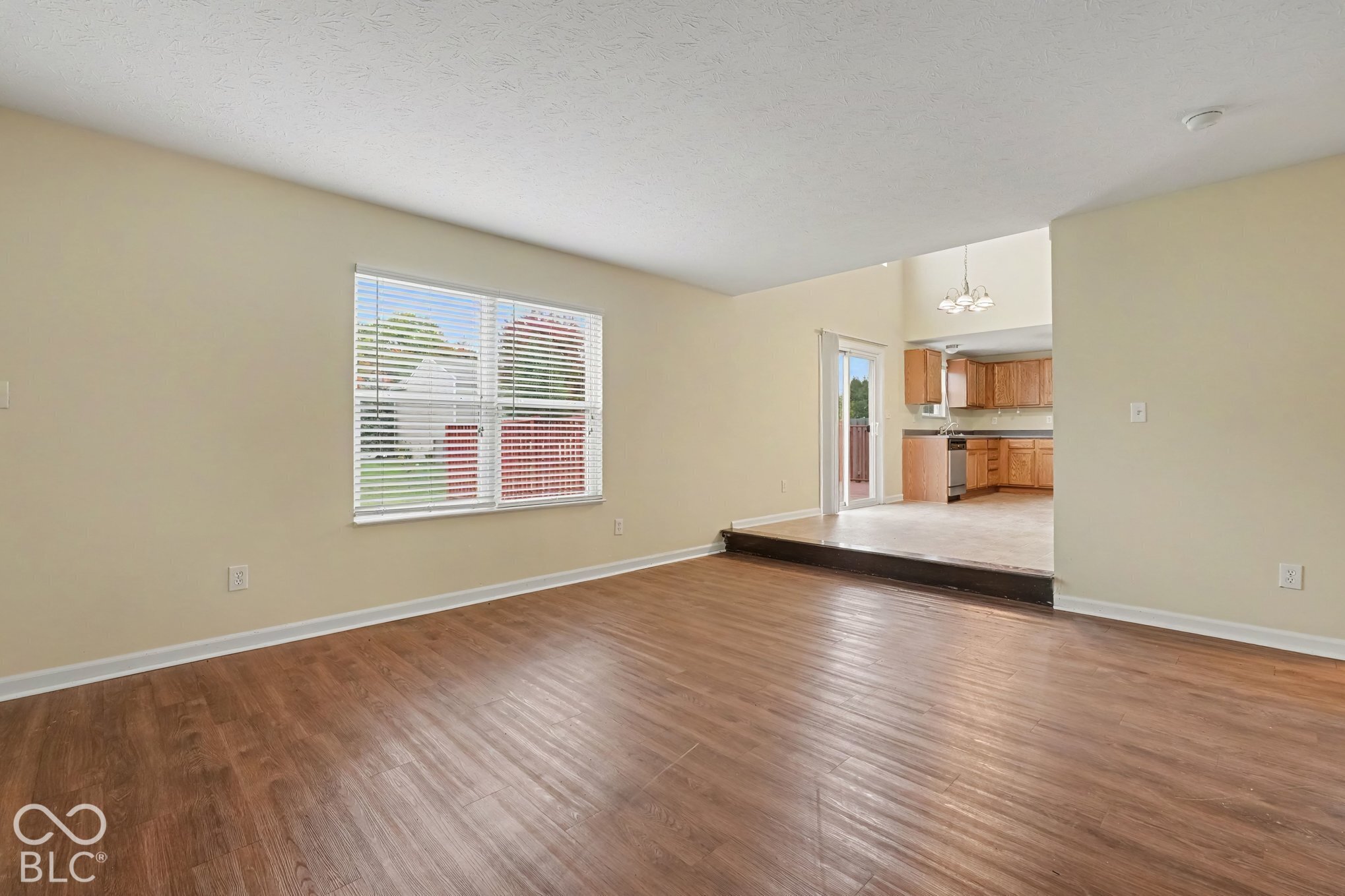 Living area featuring wood-finish flooring, a multi-pane window, split-level architectural detail, and sliding glass doors