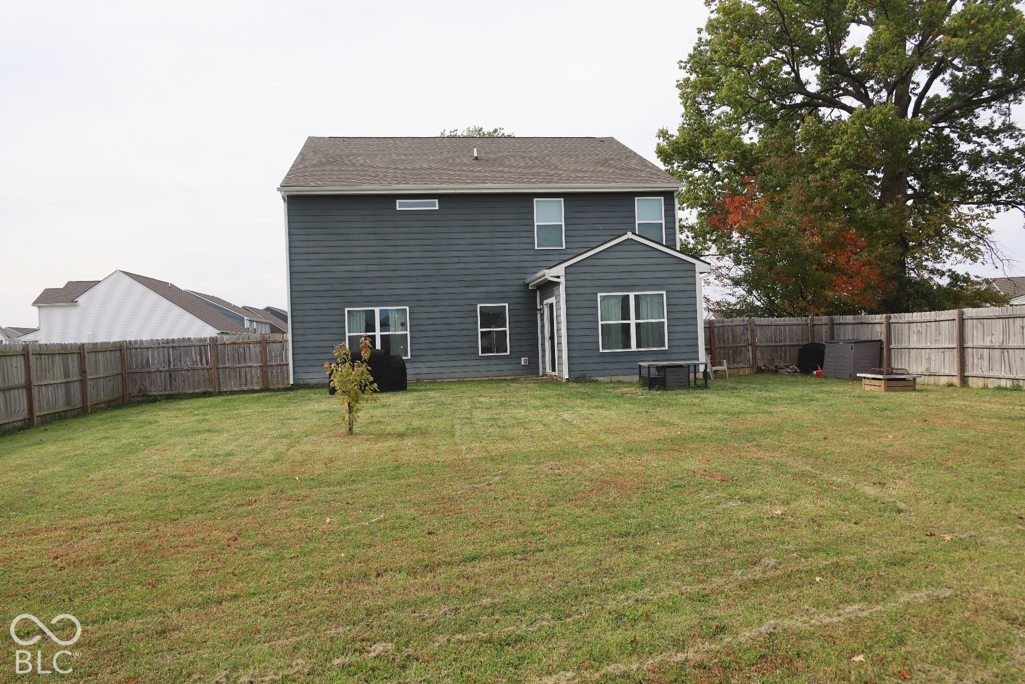 Rear exterior featuring horizontal lap siding, a shingled roof, multi-pane windows, and a fenced-in backyard