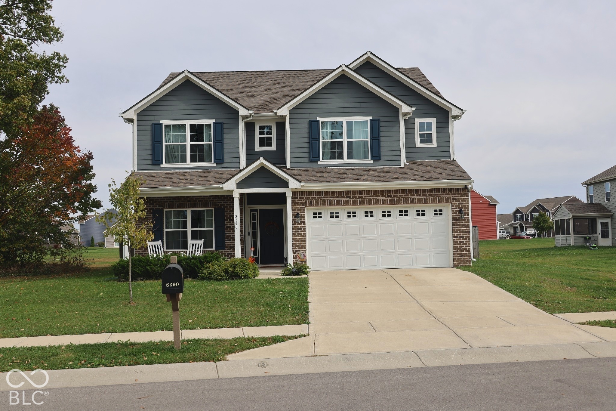 Two-story residence featuring a brick and horizontal siding exterior, dual gabled rooflines, two-car garage, and decorative shutters