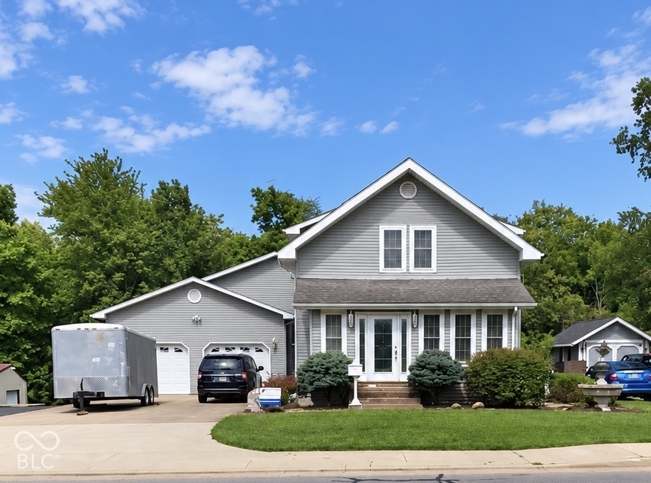 Traditional two-story exterior featuring light-toned horizontal siding, a gabled roofline, an attached two-car garage, and manicured landscaping Traditional two-story exterior featuring light-toned horizontal siding, a gabled roofline, an attached two-car garage, and manicured landscaping