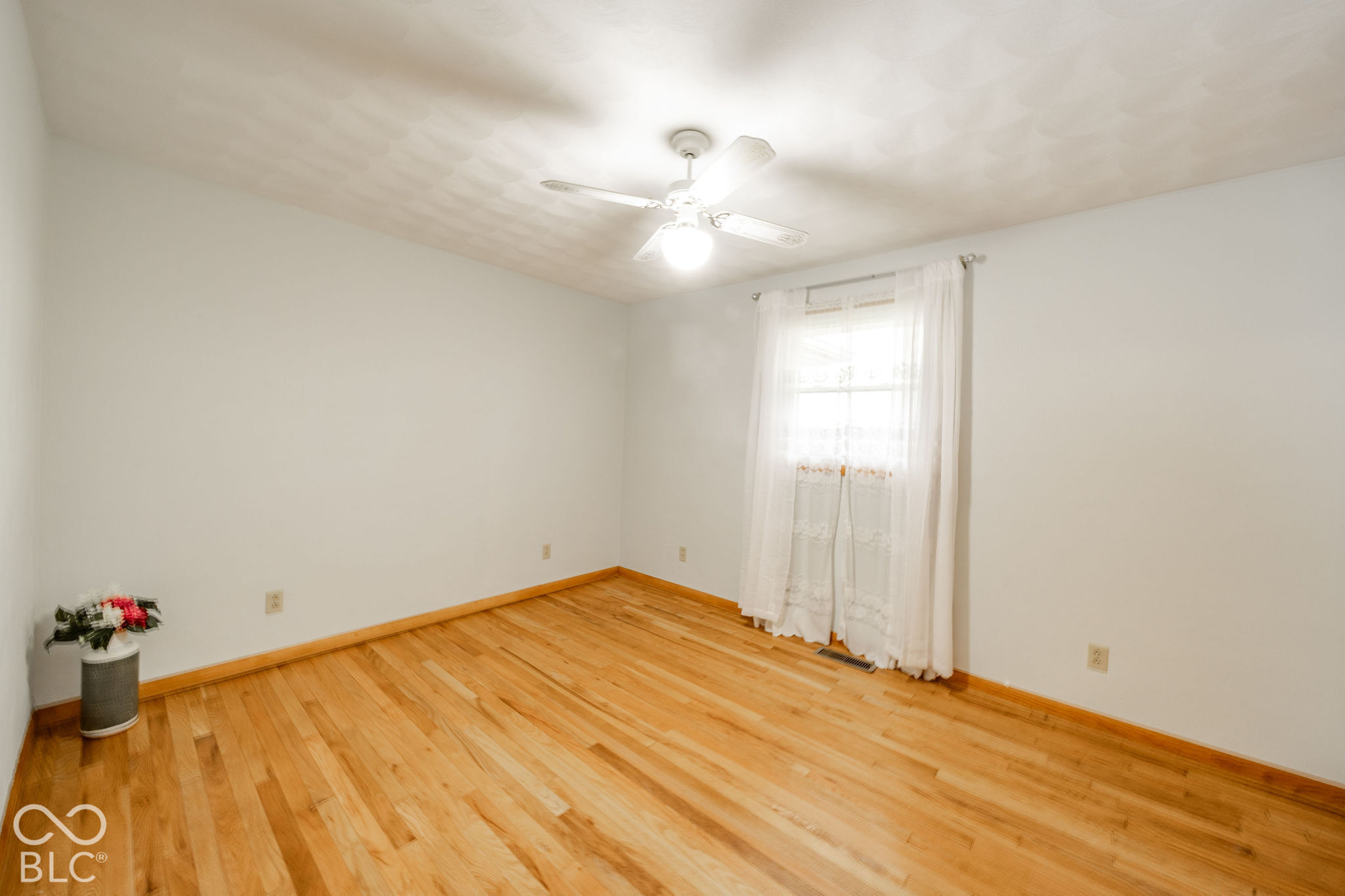 Room featuring wood-finish flooring, textured ceiling, and white ceiling fan with integrated lighting