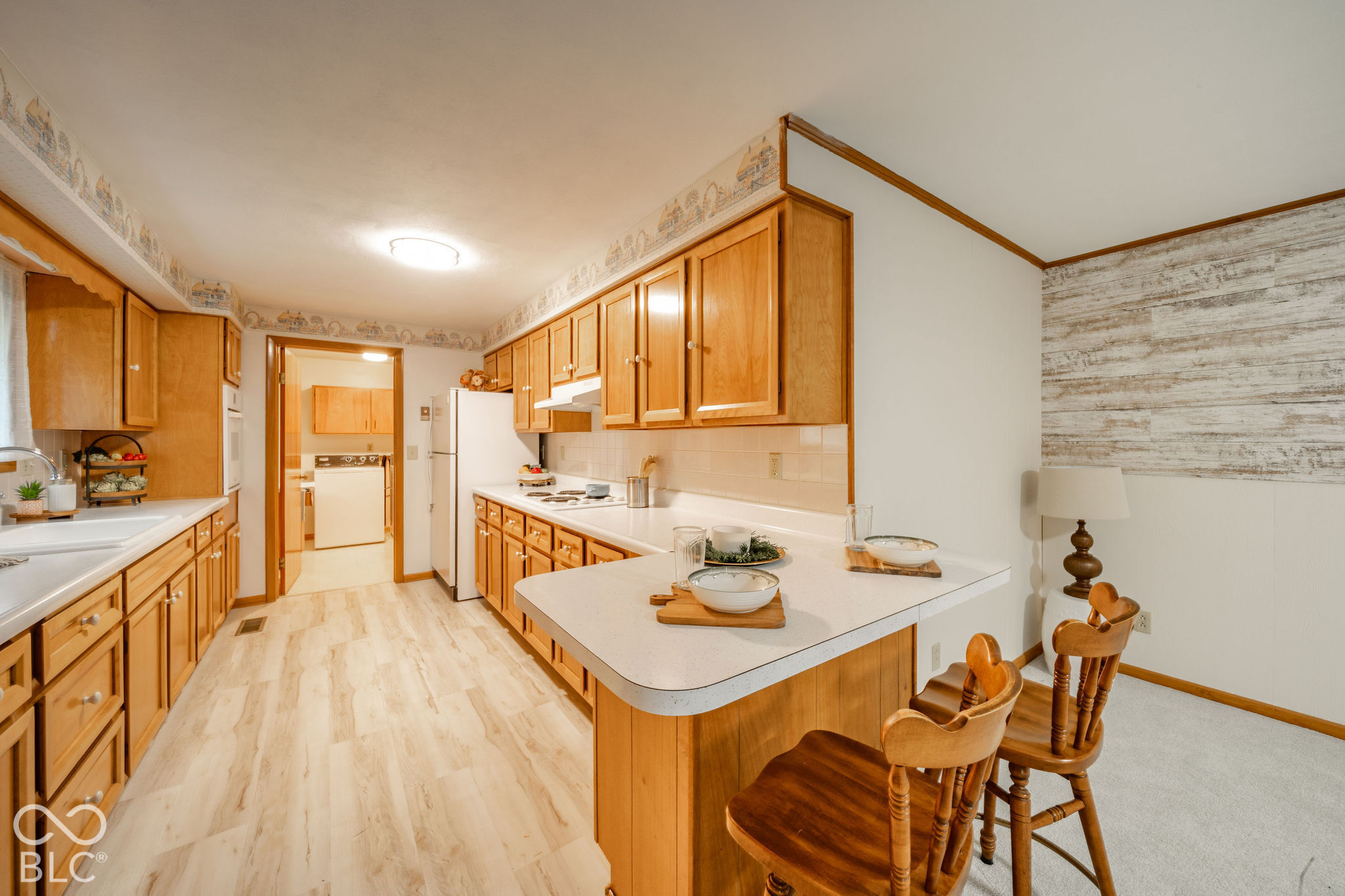 Kitchen featuring natural wood cabinetry, solid surface countertops, peninsula bar, and wood-finish flooring