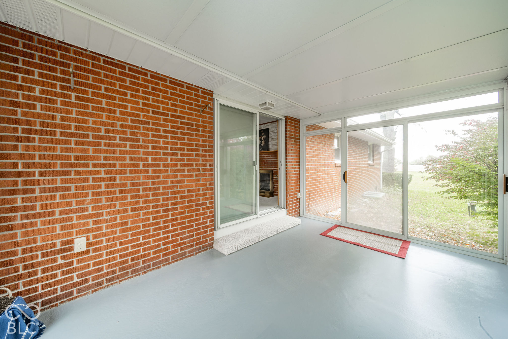 Enclosed sunroom featuring exposed brick walls, expansive sliding glass doors, and solid surface flooring