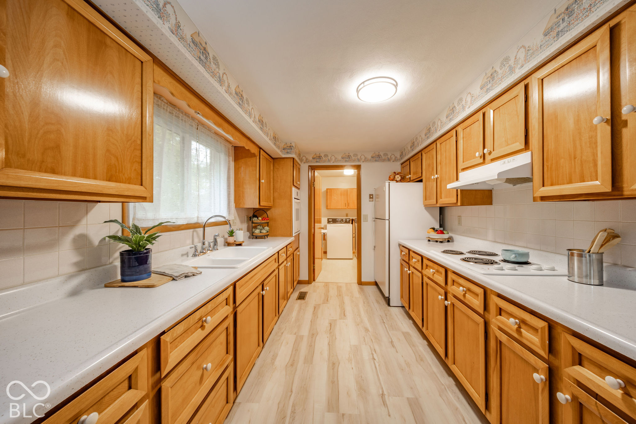 Kitchen featuring wood cabinetry, solid-surface countertops, tile backsplash, built-in electric cooktop, and wood-finish flooring