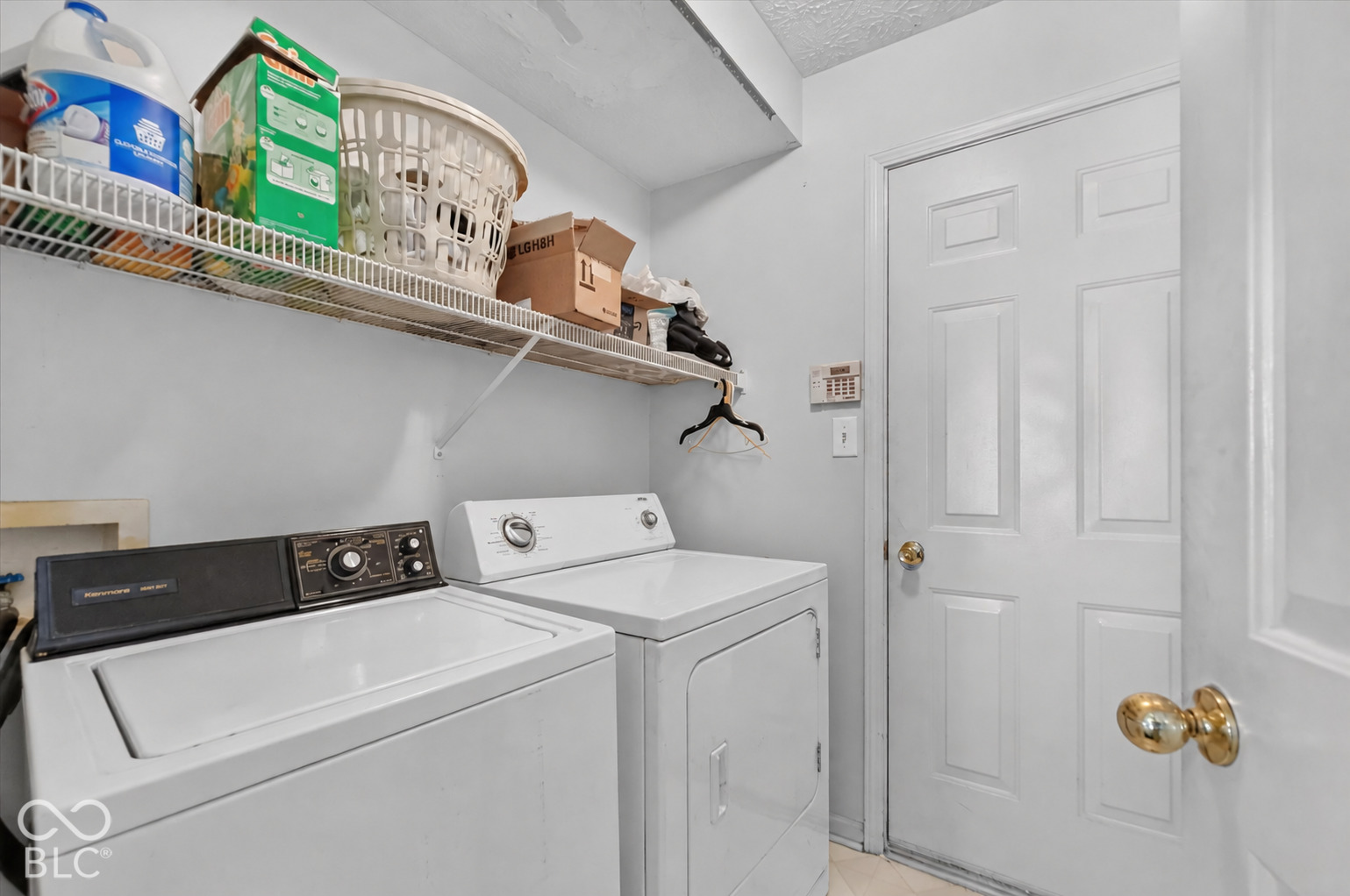Laundry room featuring wire shelving and a paneled door with brass-finish hardware