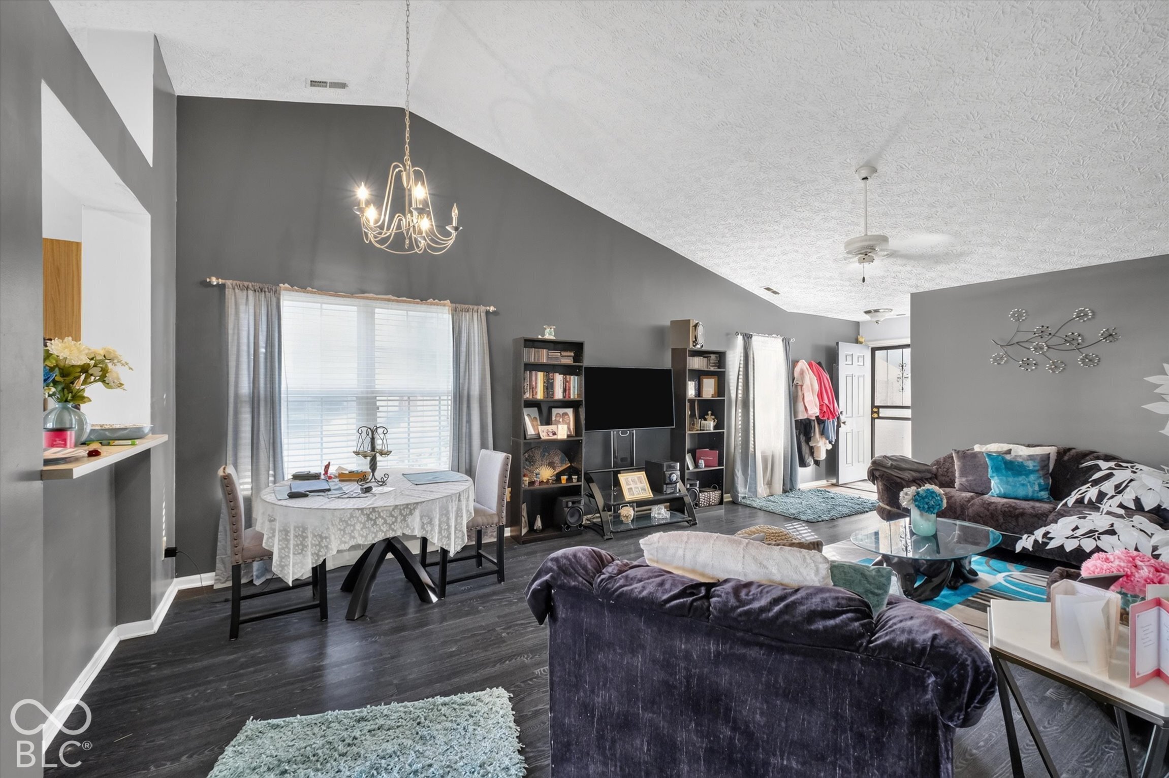 Vaulted ceilings, wood-finish flooring, and an elevated chandelier featuring multi-bulb lighting