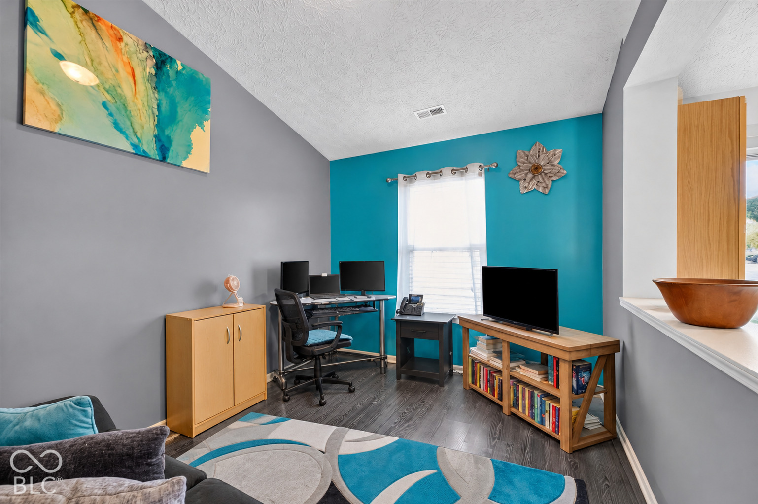 Vaulted ceiling, wood-finish flooring, and natural lighting provided by a central window