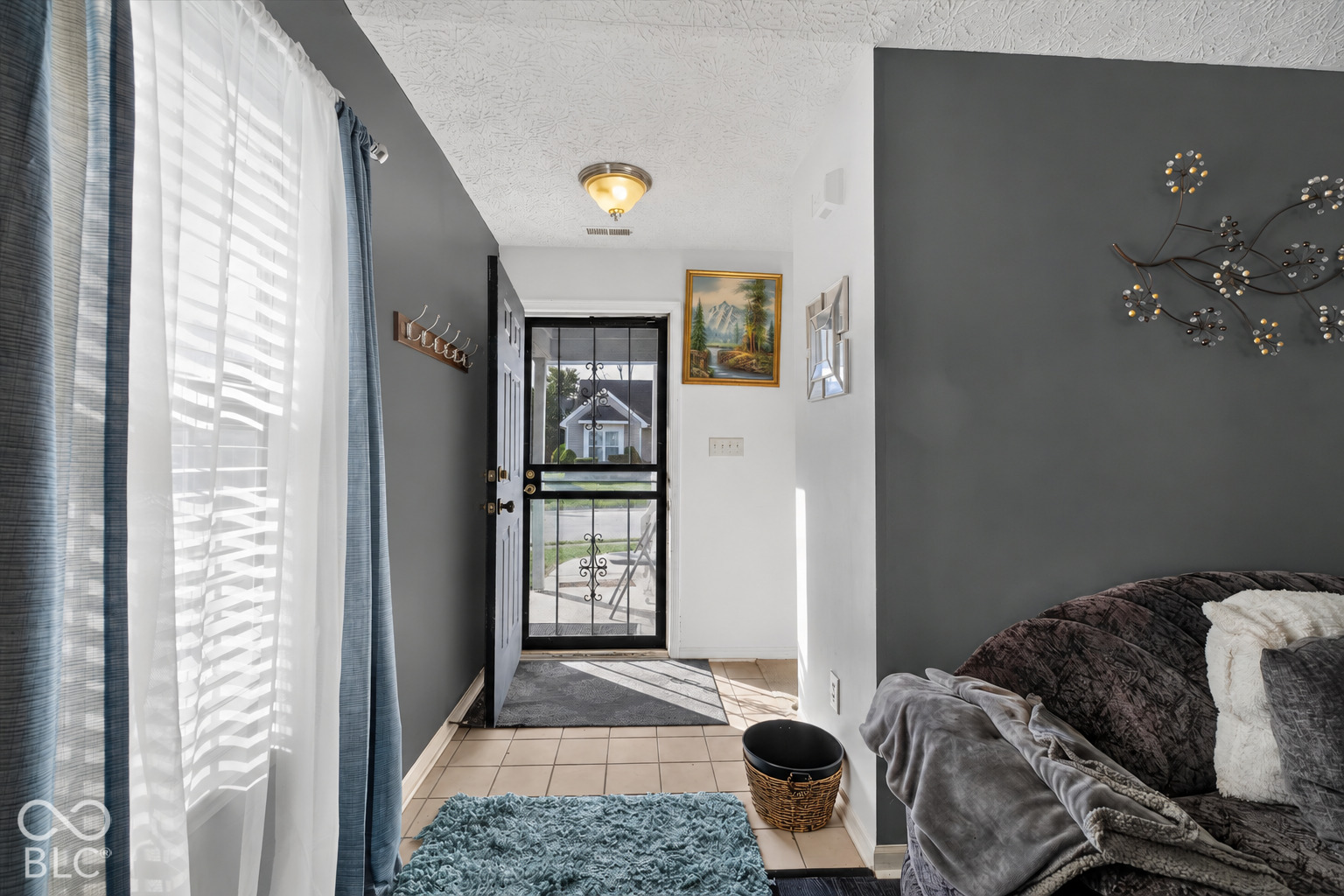 Entryway featuring ceramic tile flooring, a glass-paneled storm door, and decorative wall-mounted coat hooks