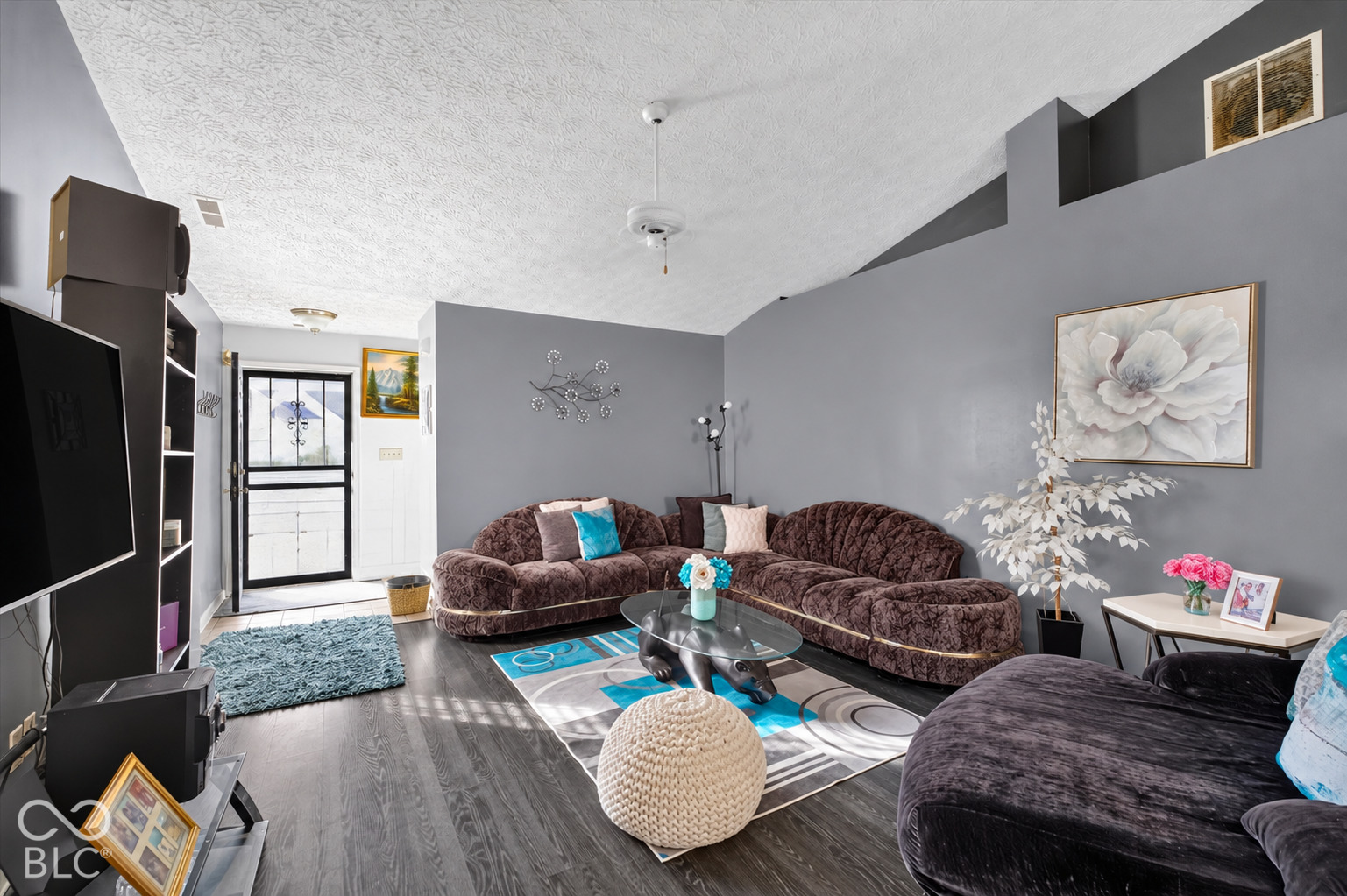 Living area featuring a vaulted ceiling, wood-finish flooring, and a ceiling fan