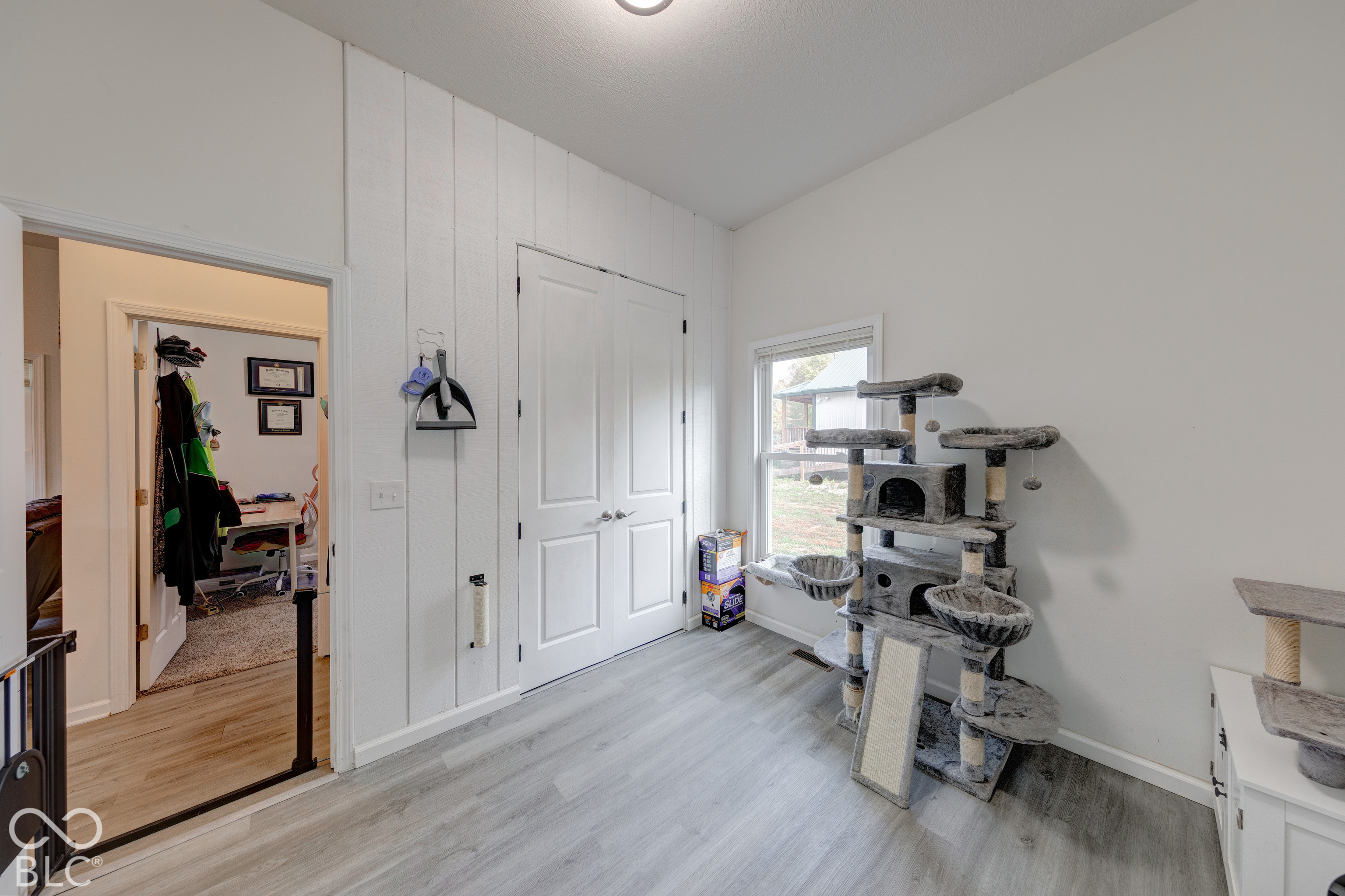 Interior room featuring wood-finish flooring, white vertical plank wall detailing, and white double doors