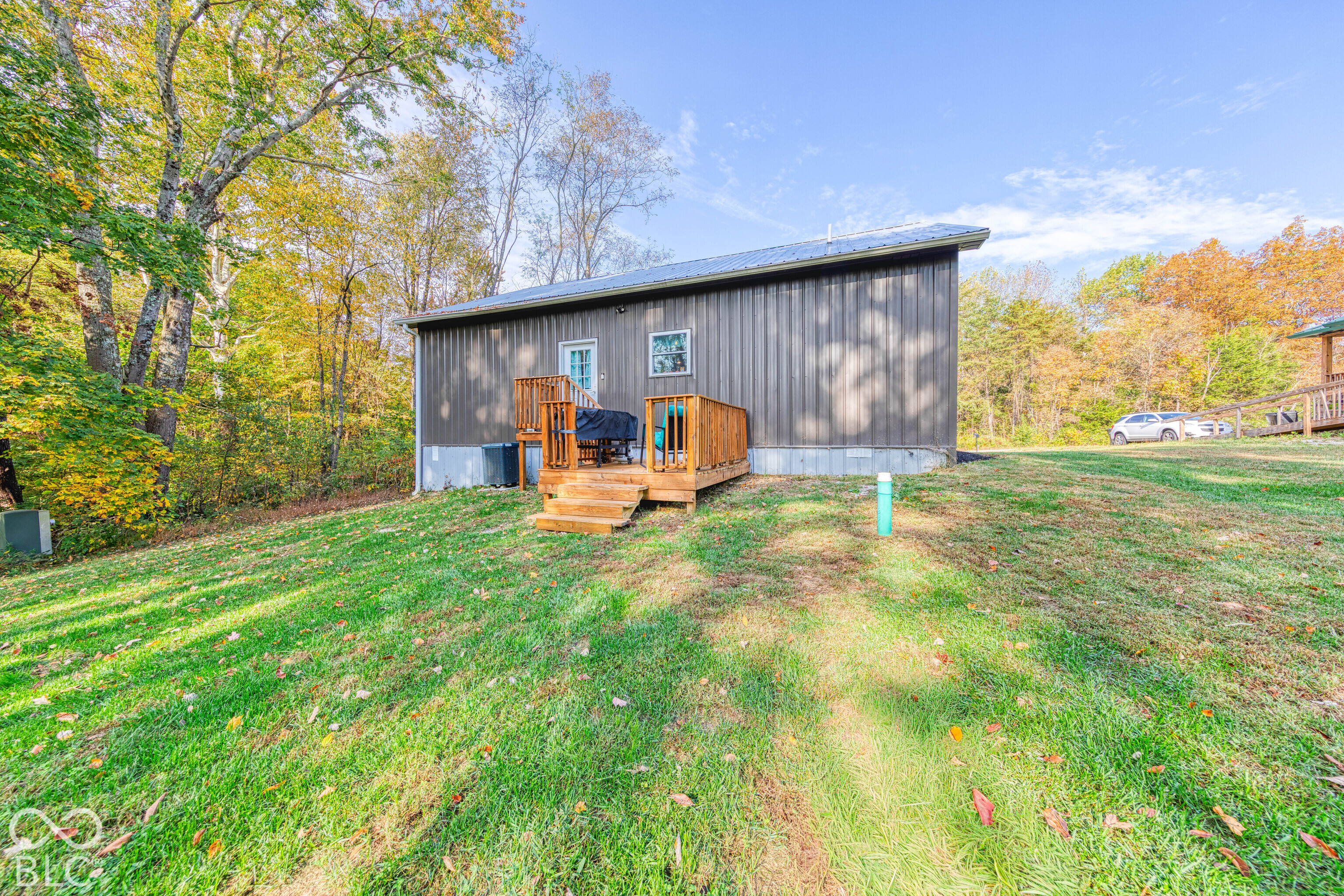 Vertical metal siding exterior with a wood-railing deck and sloped lot