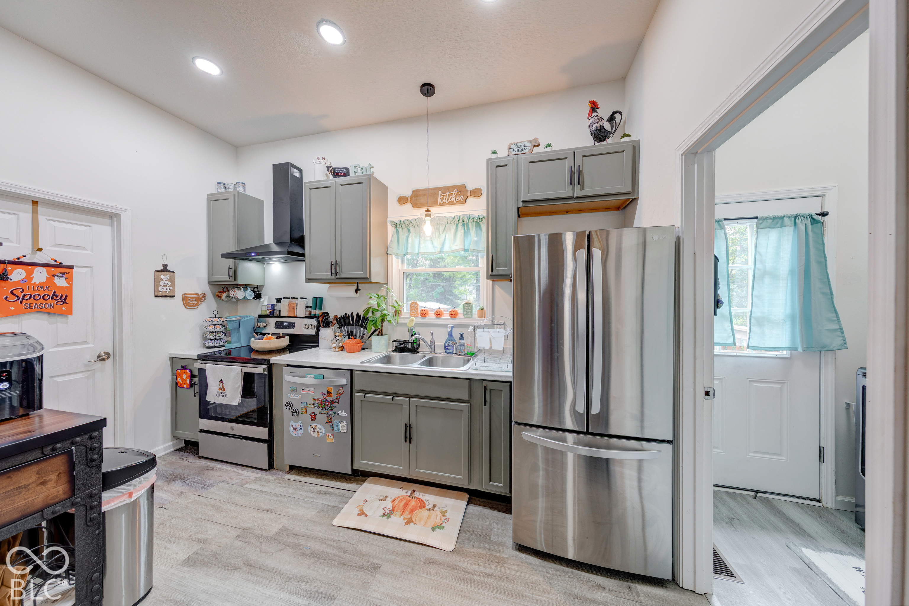 Kitchen featuring grey cabinetry, stainless steel appliances, a black range hood, recessed lighting, and wood-finish flooring