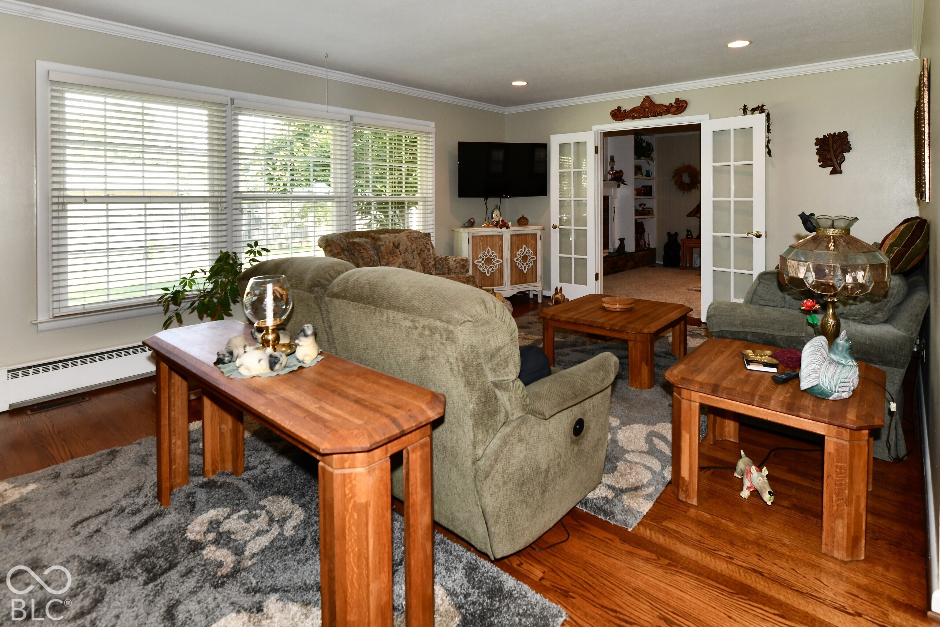 Living area featuring wood-finish flooring, recessed lighting, crown molding, and white-trimmed French doors