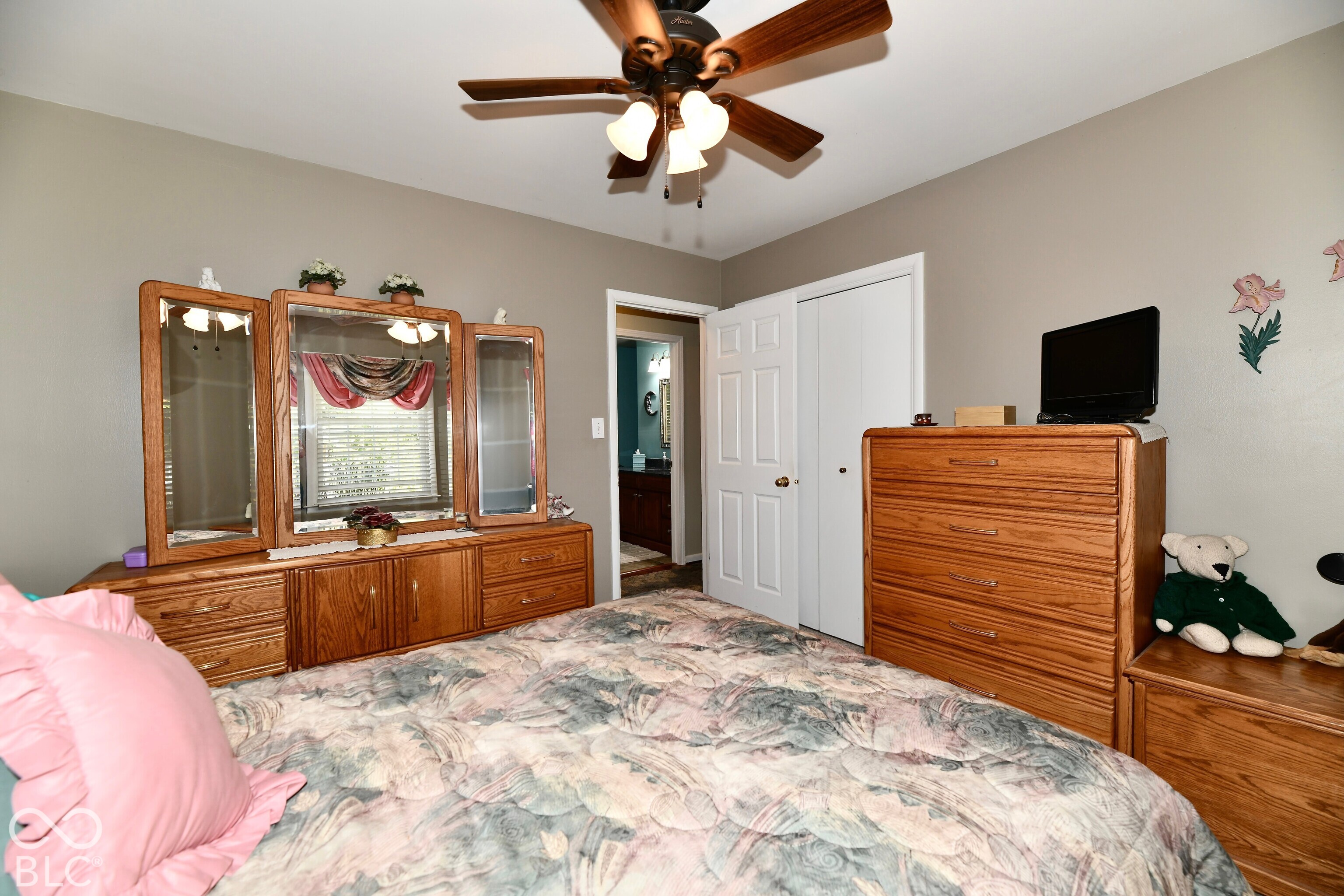 Room featuring a ceiling fan with multi-light fixture, white paneled closet doors, and neutral wall tones