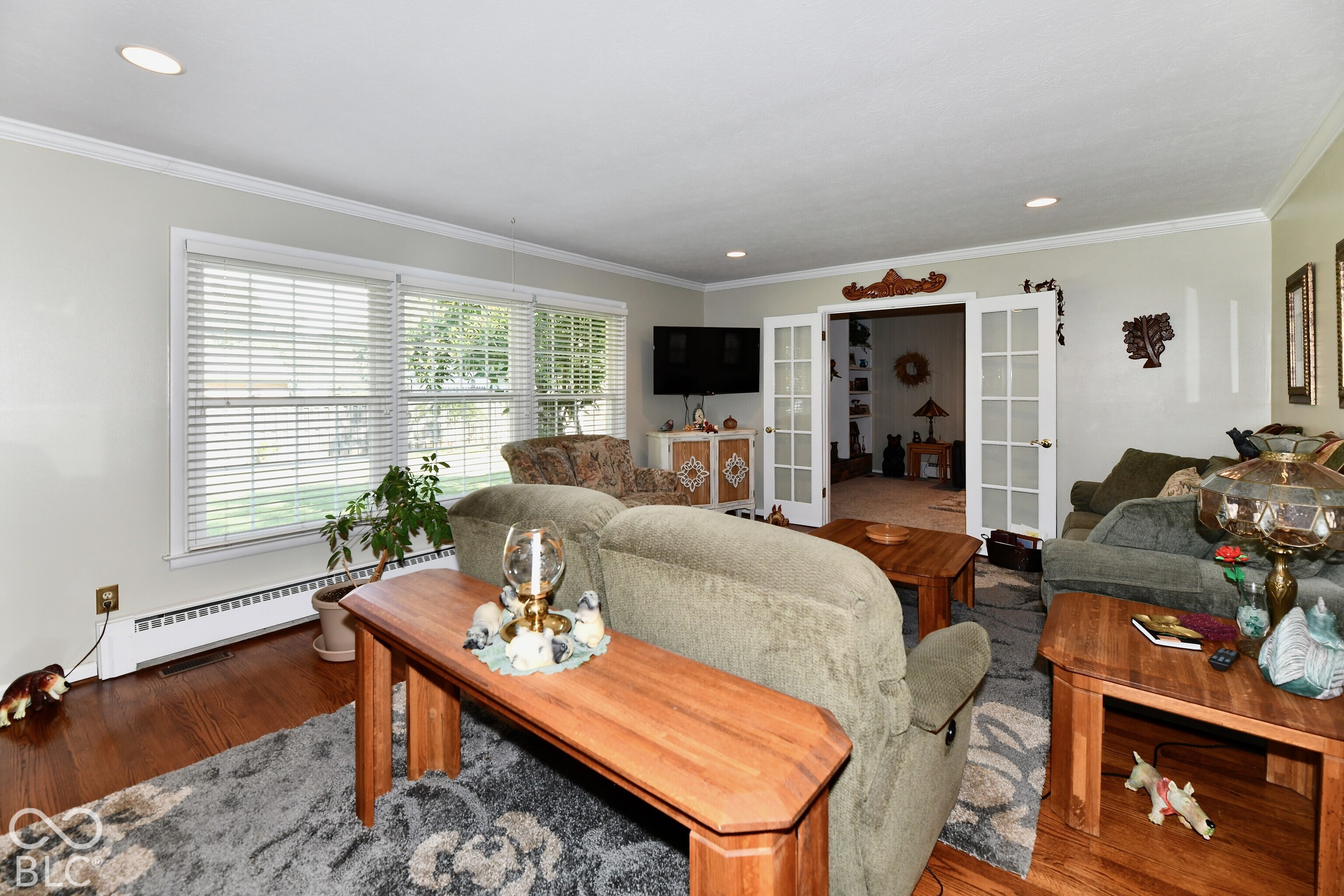 Living area featuring wood-finish flooring, recessed lighting, and large windows with horizontal blinds