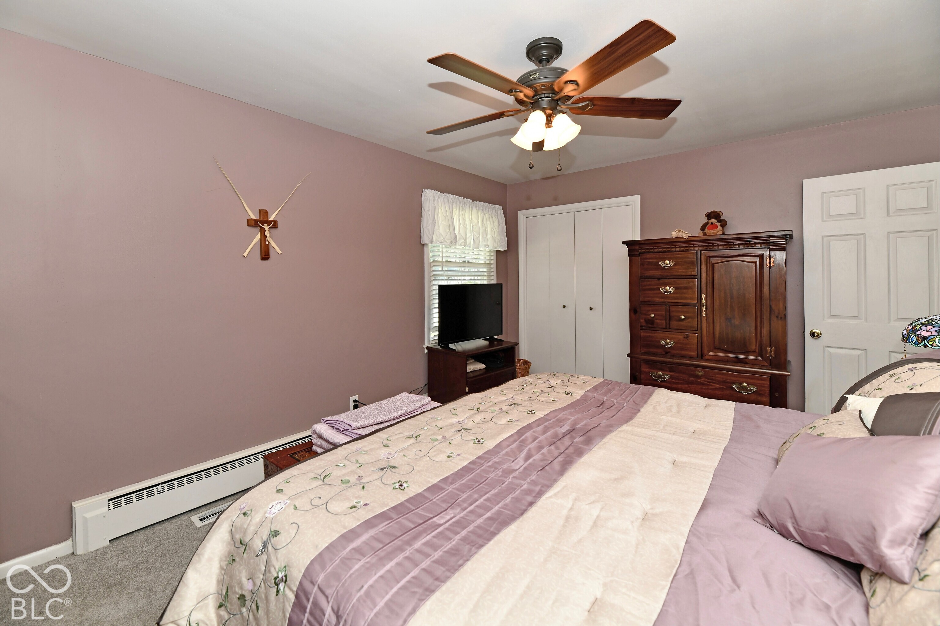 Room featuring neutral-toned carpeting, dual-panel closet doors, a multi-light ceiling fan, and a six-panel interior door