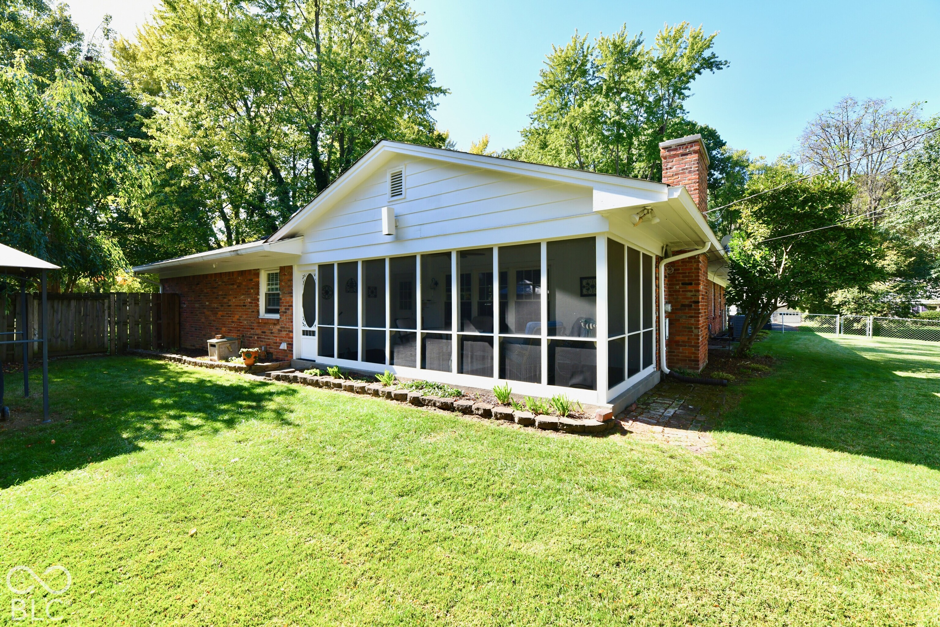 Exterior featuring a brick and white siding facade, a screened-in porch, and a masonry chimney