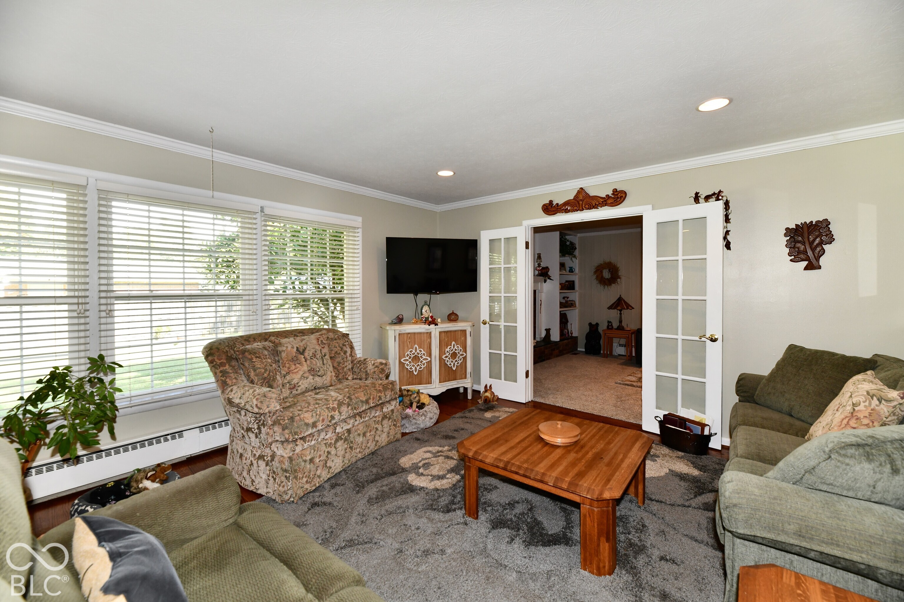 Large windows with horizontal blinds, recessed lighting, crown molding, and glass-paneled double doors