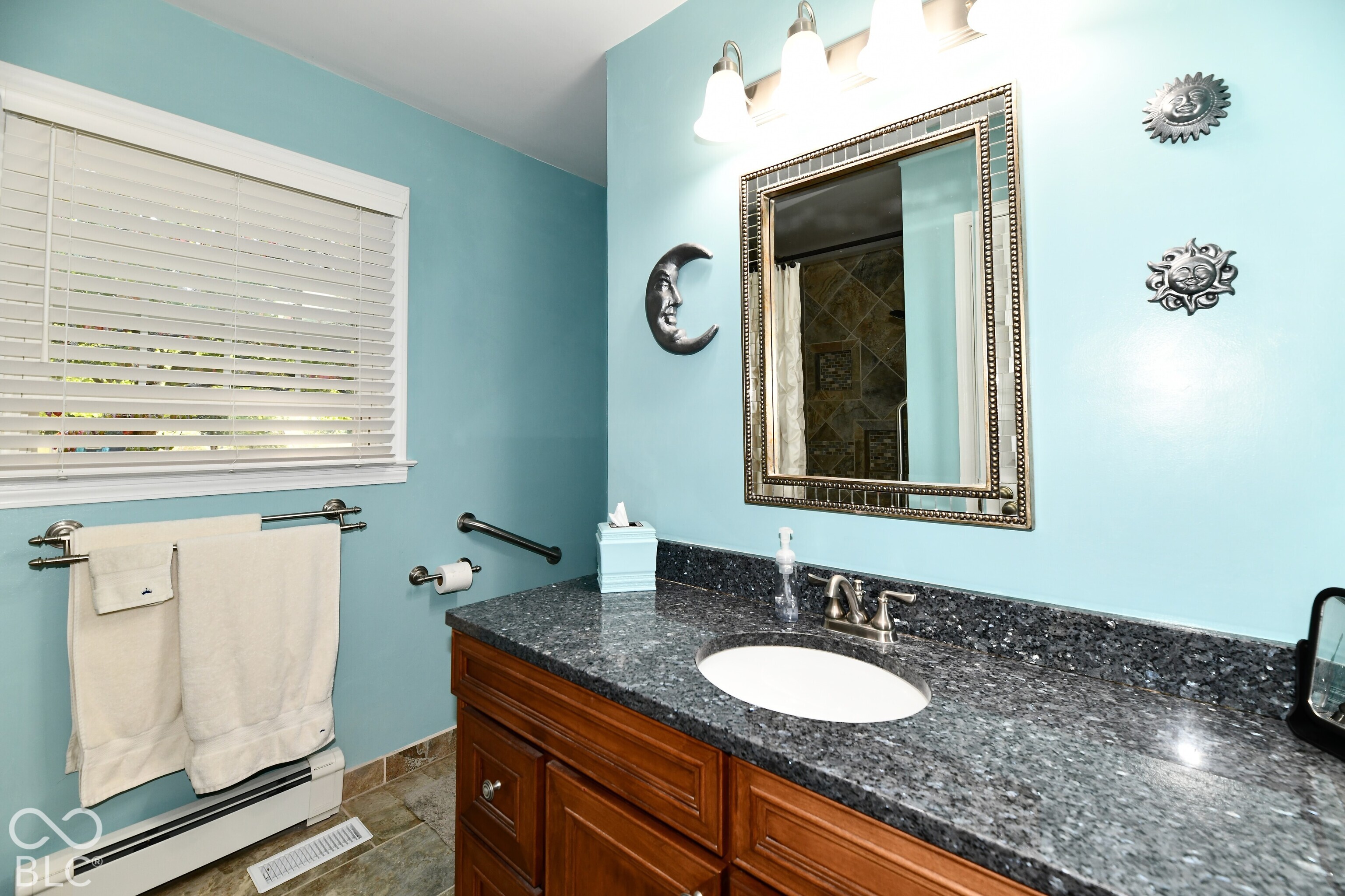 Bathroom vanity featuring a stone countertop, an integrated undermount oval sink, wooden cabinetry, and a three-light wall-mounted fixture