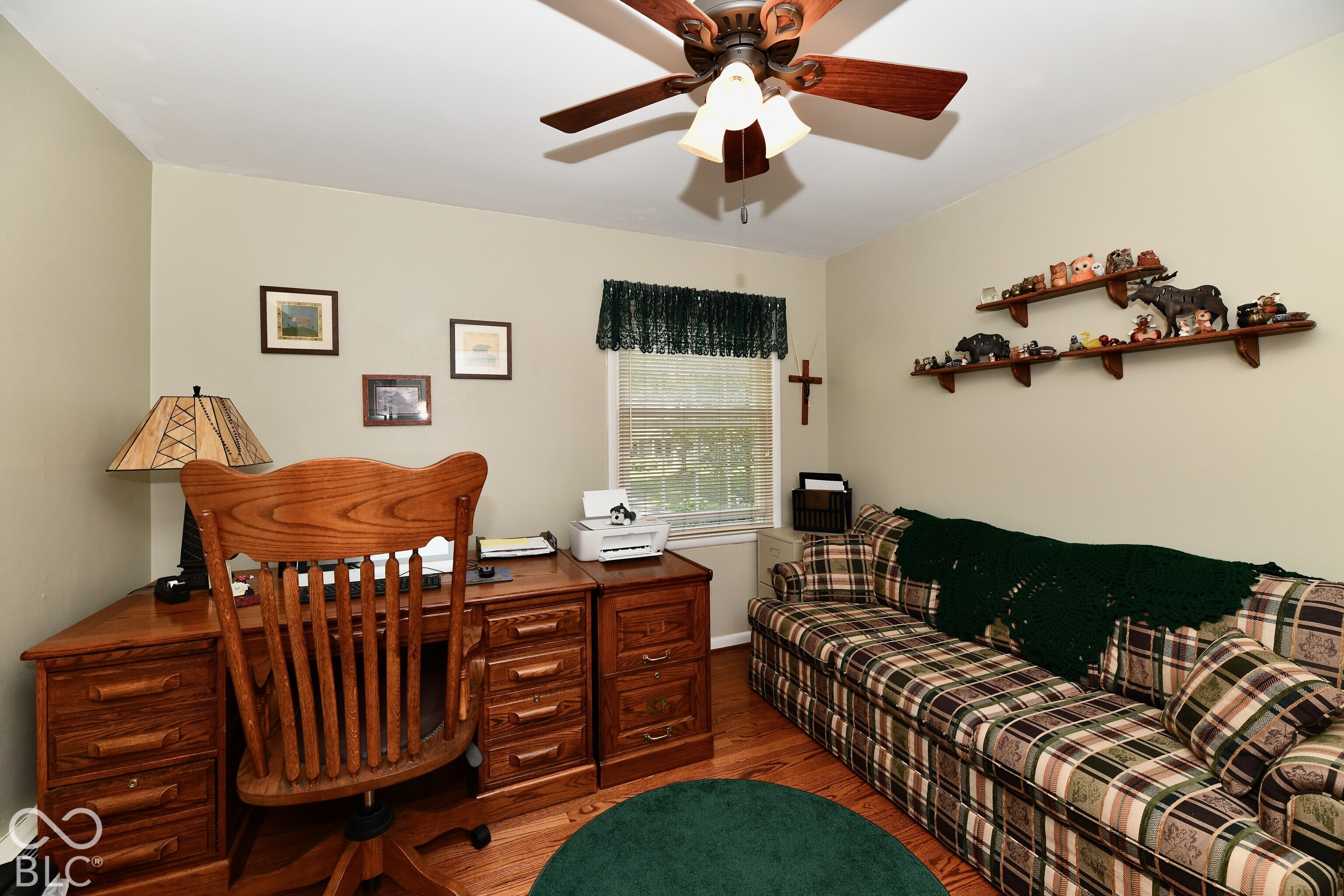 Room featuring wood-finish flooring, a ceiling fan with integrated lighting, and a window with trim