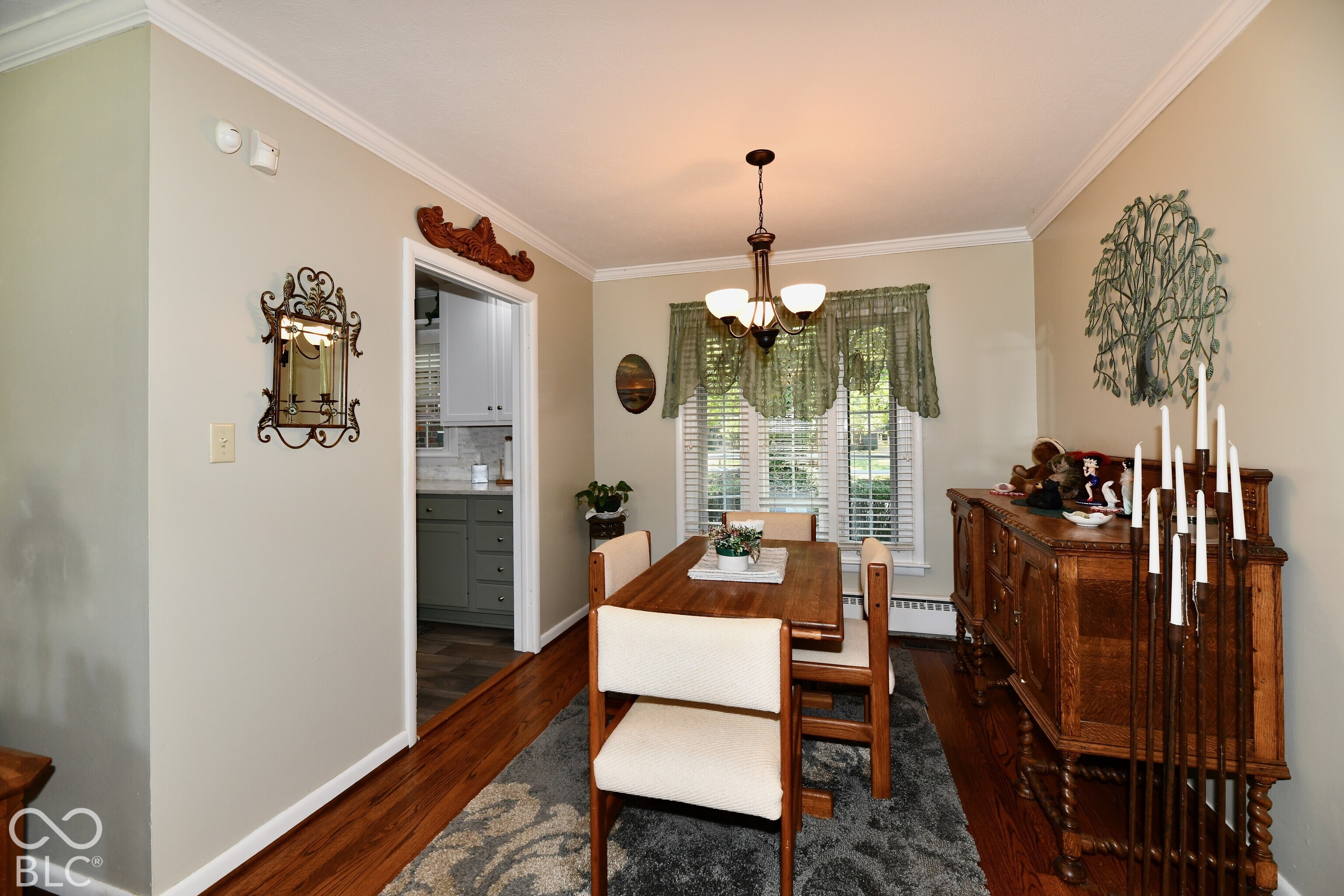 Dining area featuring hardwood flooring, crown molding, multi-light chandelier, and bay window