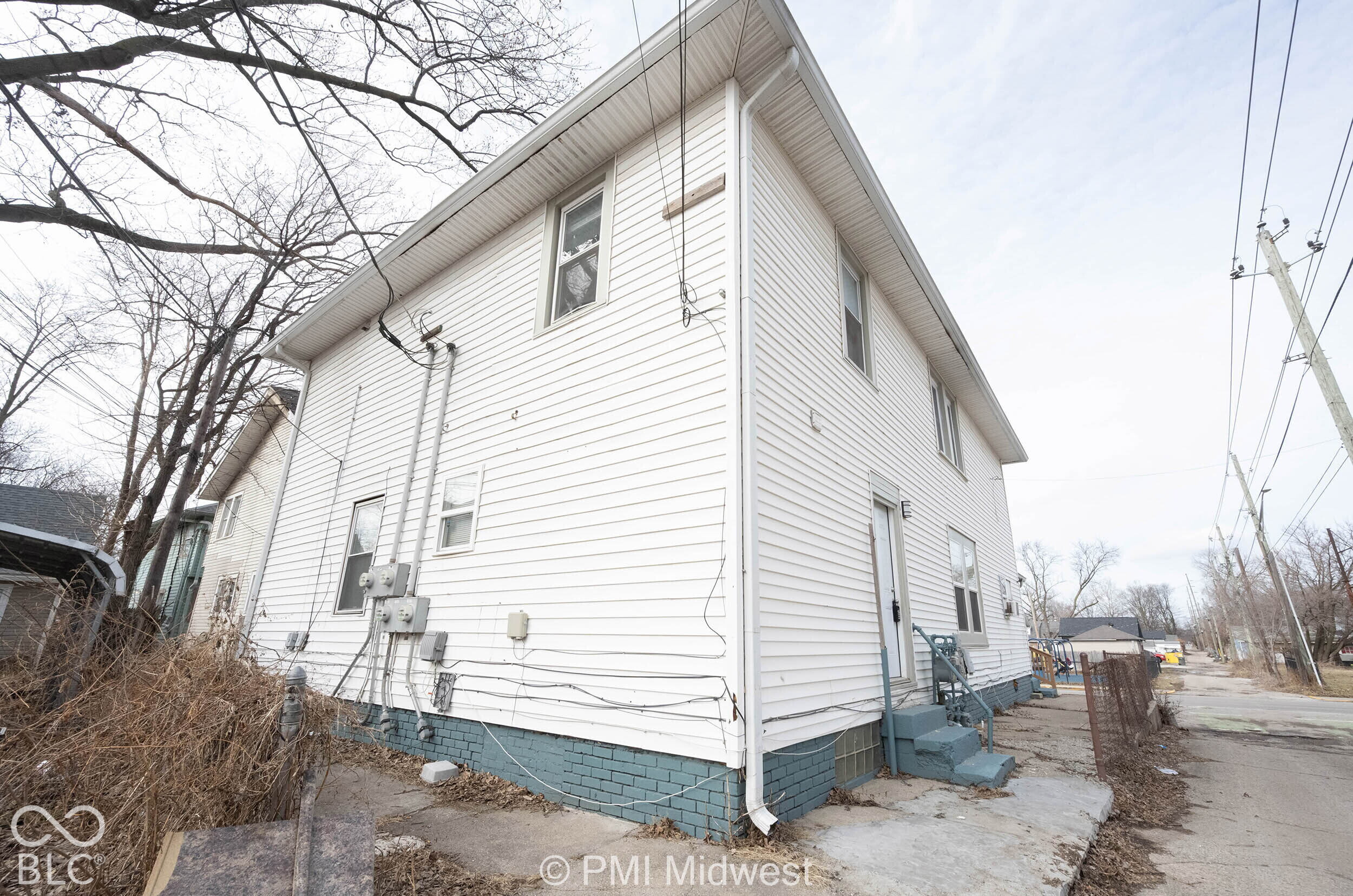 Two-story exterior featuring white horizontal siding and a painted masonry foundation