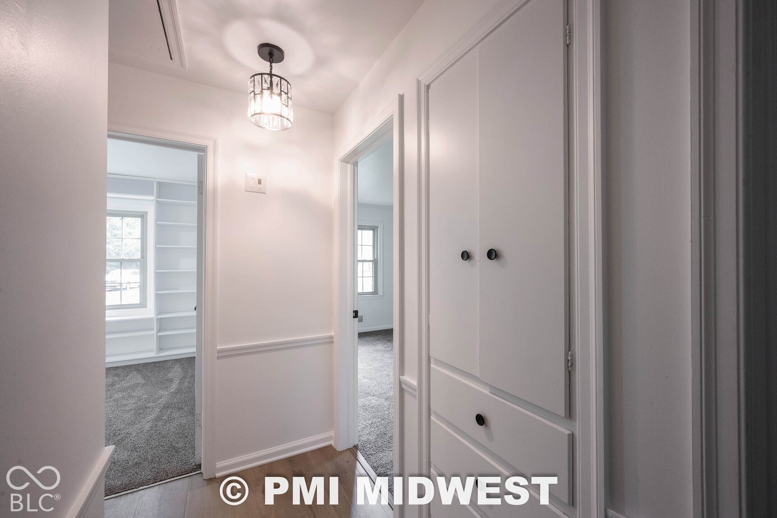 Hallway featuring built-in floor-to-ceiling storage cabinetry, decorative wainscoting, drum-style ceiling lighting, and wood-finish flooring