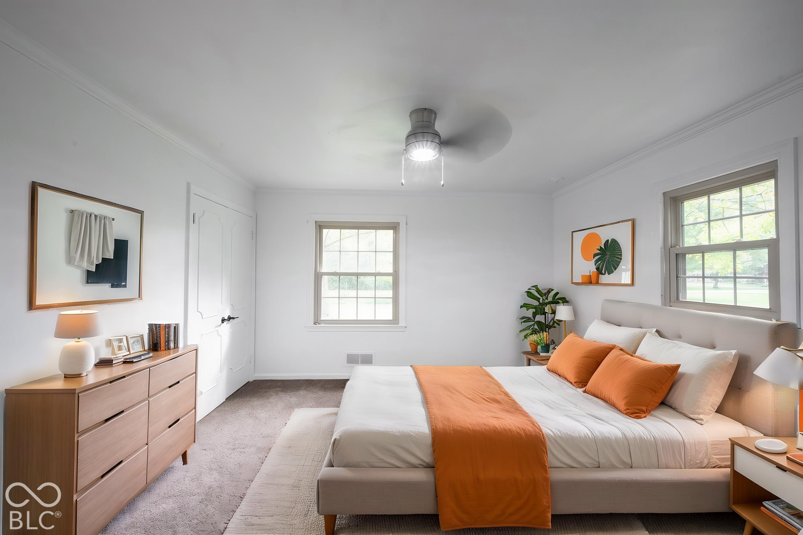 Room featuring neutral carpeting, double-hung windows with exterior trim, and a ceiling-mounted light fixture with fan
