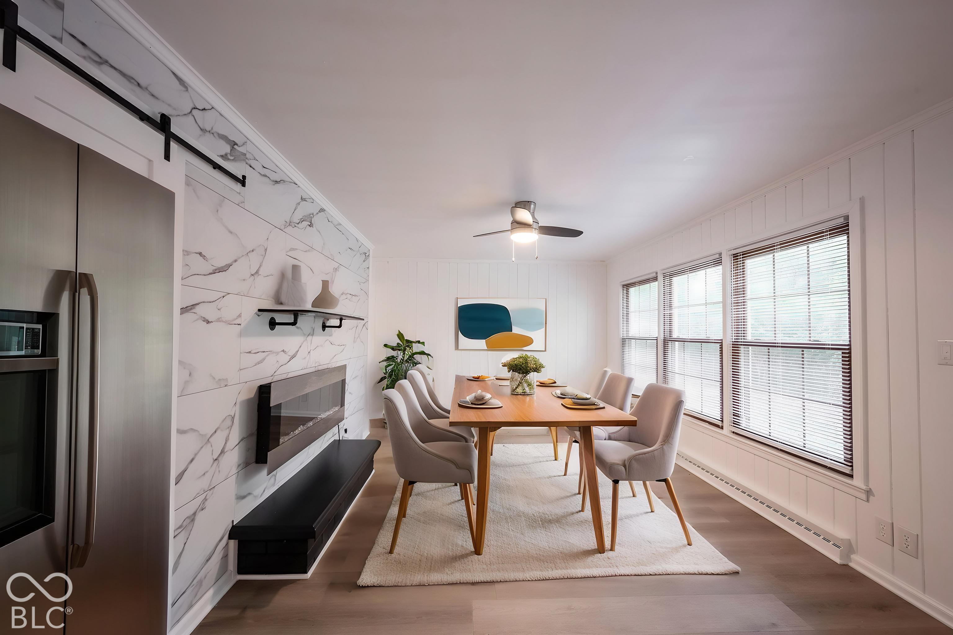 Stone-finish wall cladding with integrated wall-mounted fireplace and black shelving, vertical wood wall paneling, stainless steel refrigerator, and wood-finish flooring