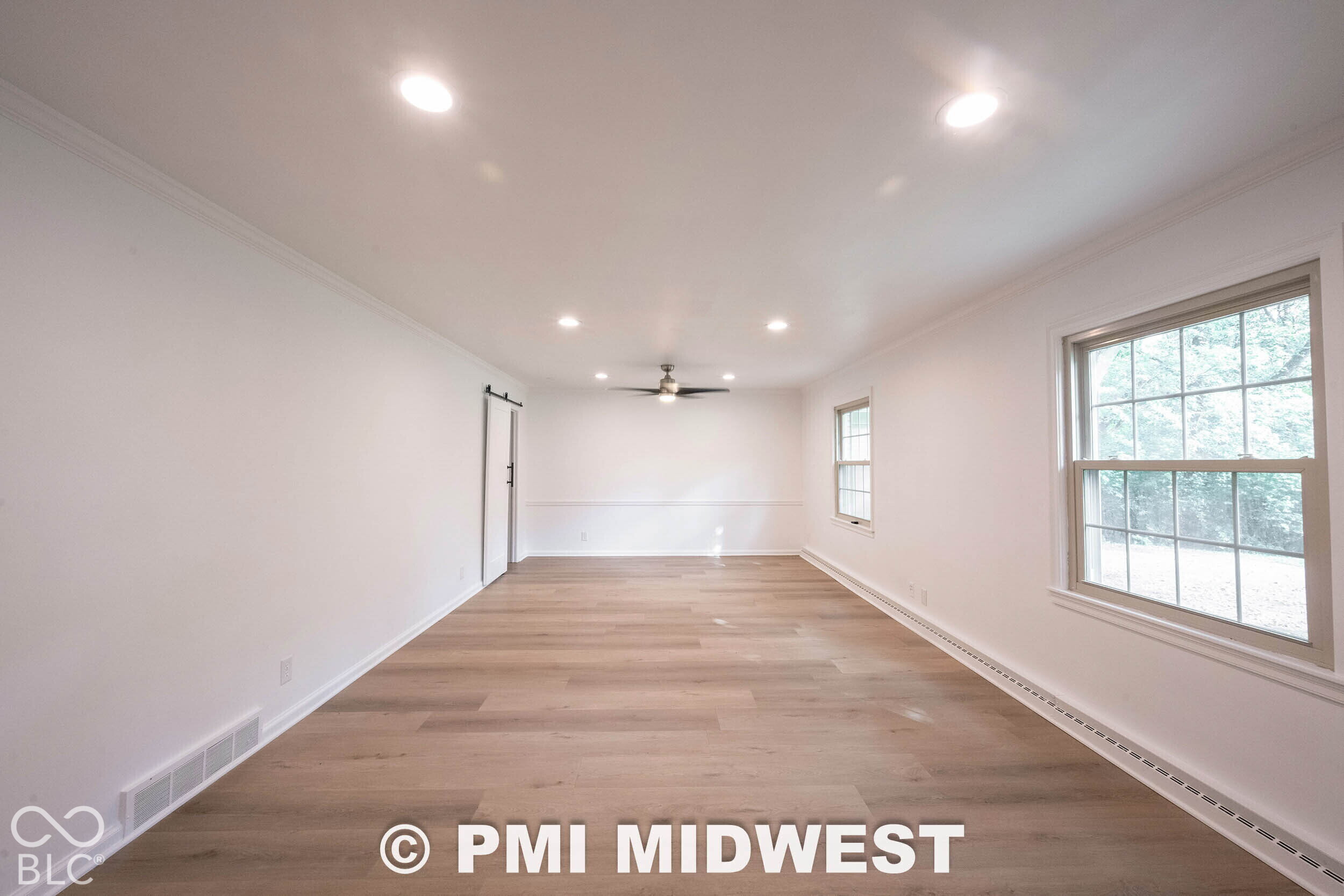 Room featuring wood-finish flooring, recessed lighting, double-hung windows, chair rail molding, and a sliding barn-style door