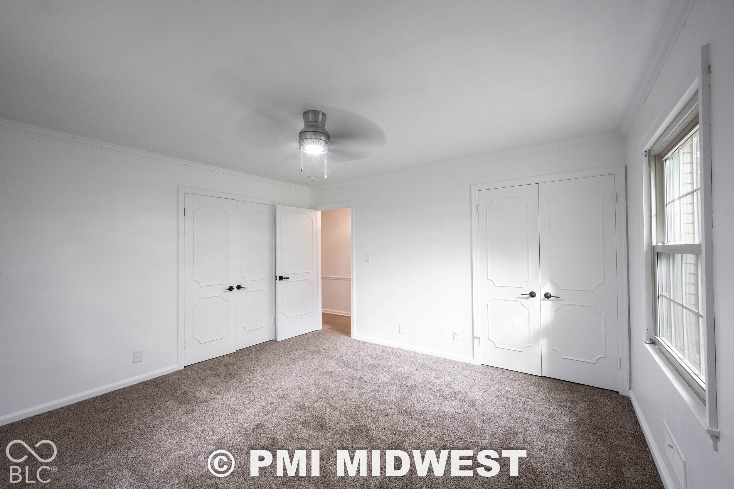 Room featuring carpeting, two sets of double doors with decorative millwork, and a ceiling-mounted light fixture with a fan