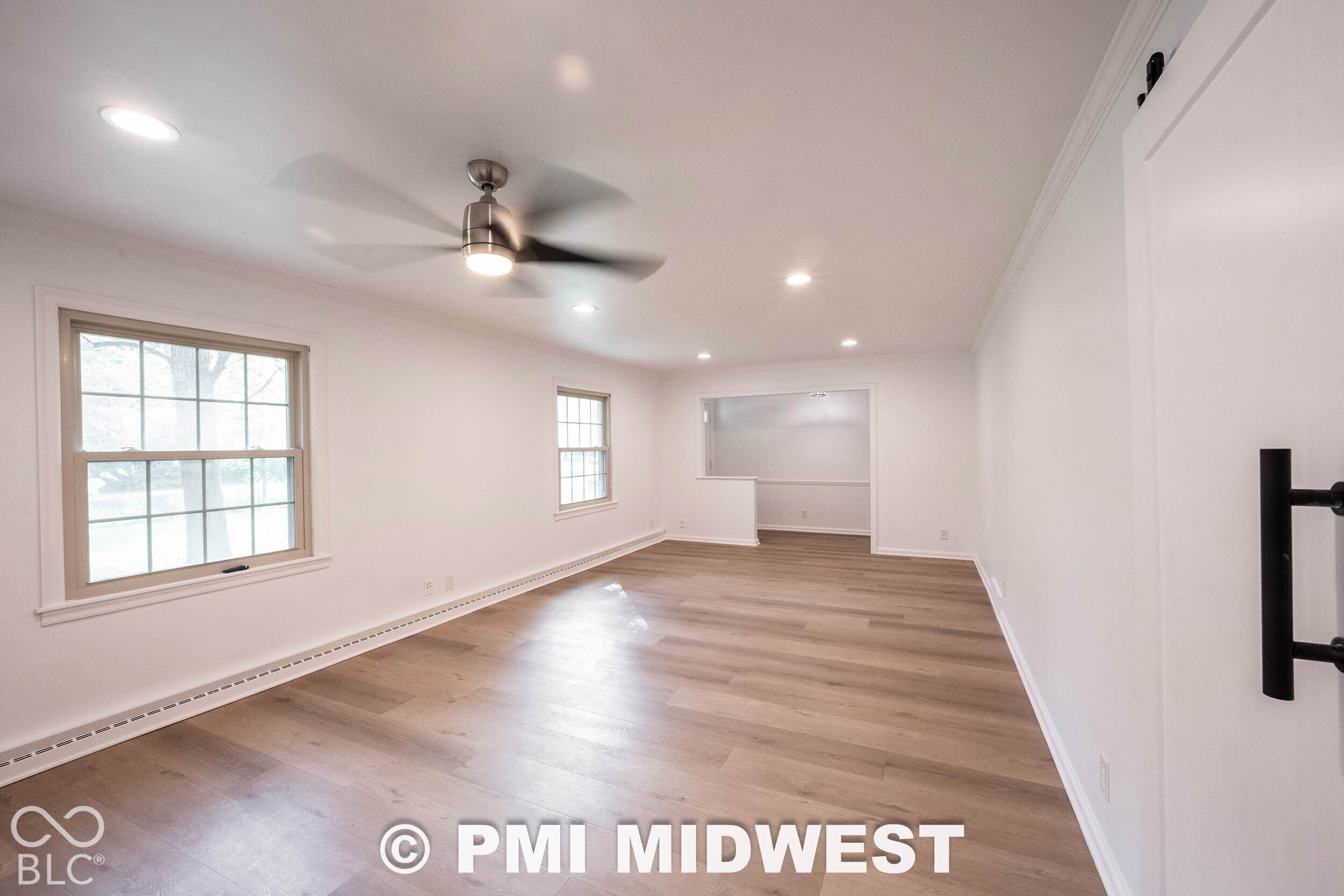 Interior space featuring wood-finish flooring, recessed lighting, a ceiling fan, grid-pattern windows, and a sliding barn-style door
