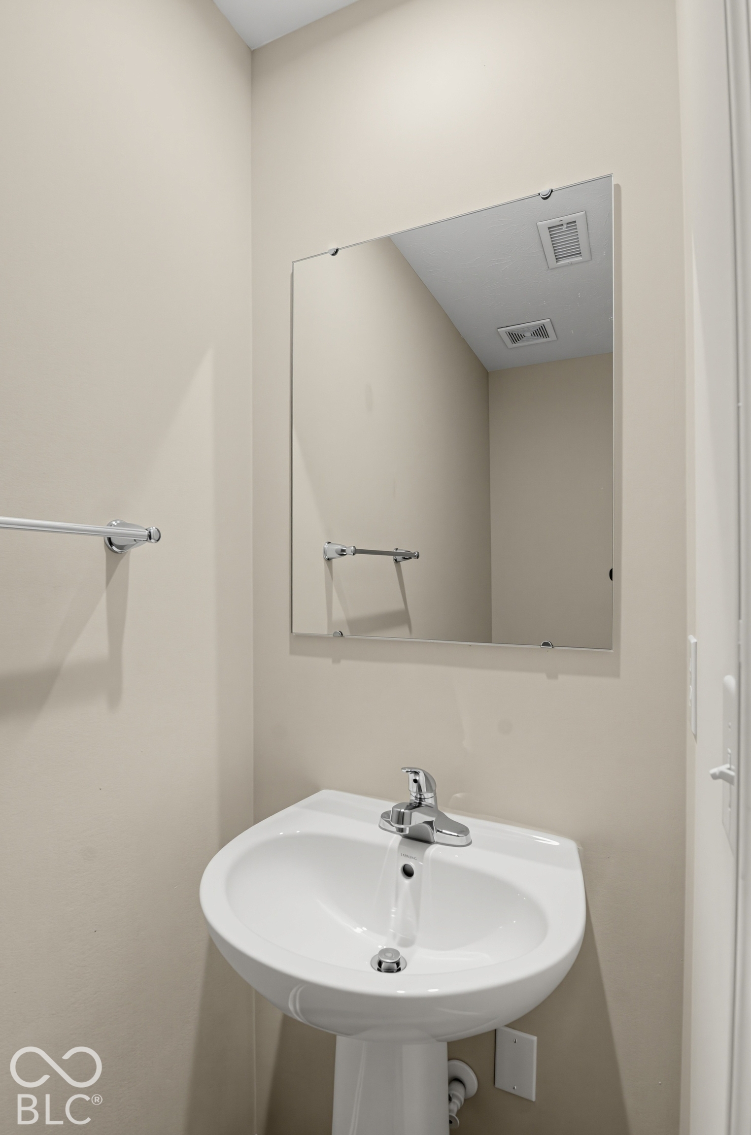White porcelain pedestal sink with a chrome single-handle faucet and a square wall-mounted mirror with chrome hardware