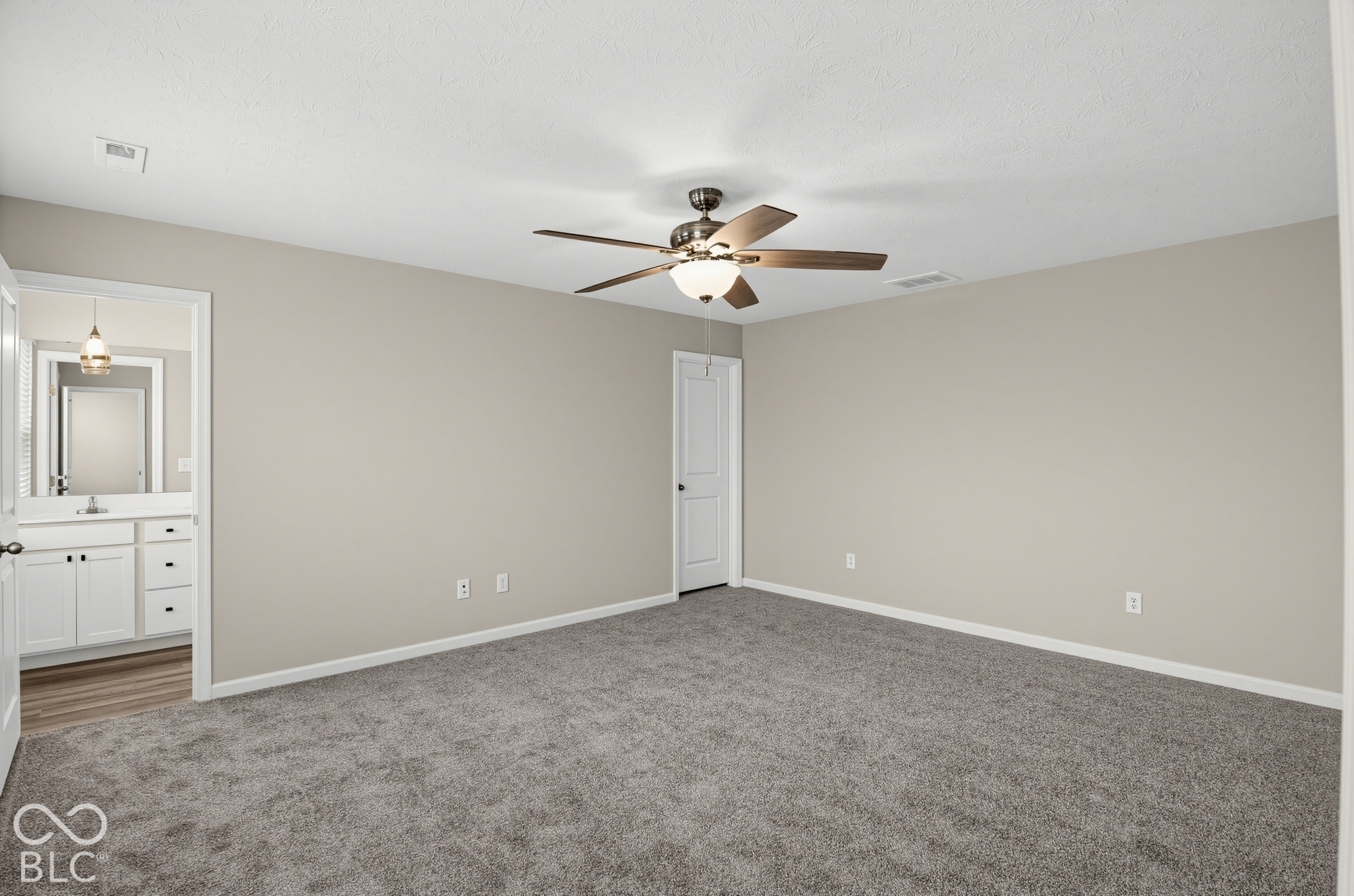 Neutral-toned interior space featuring neutral wall paint, wall-to-wall carpeting, and a ceiling fan with integrated lighting