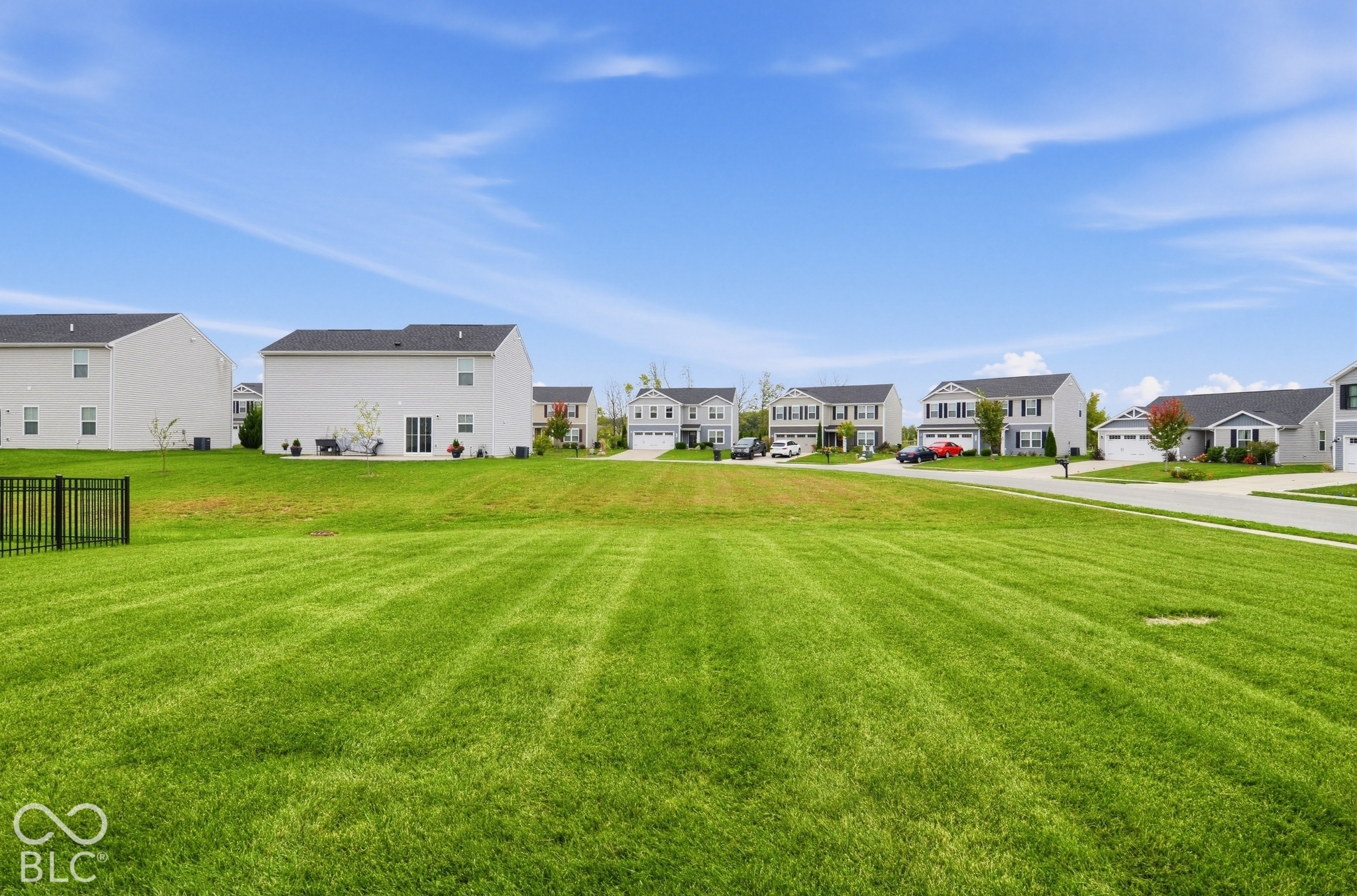 Expansive level lawn featuring manicured turf and a black metal perimeter fence