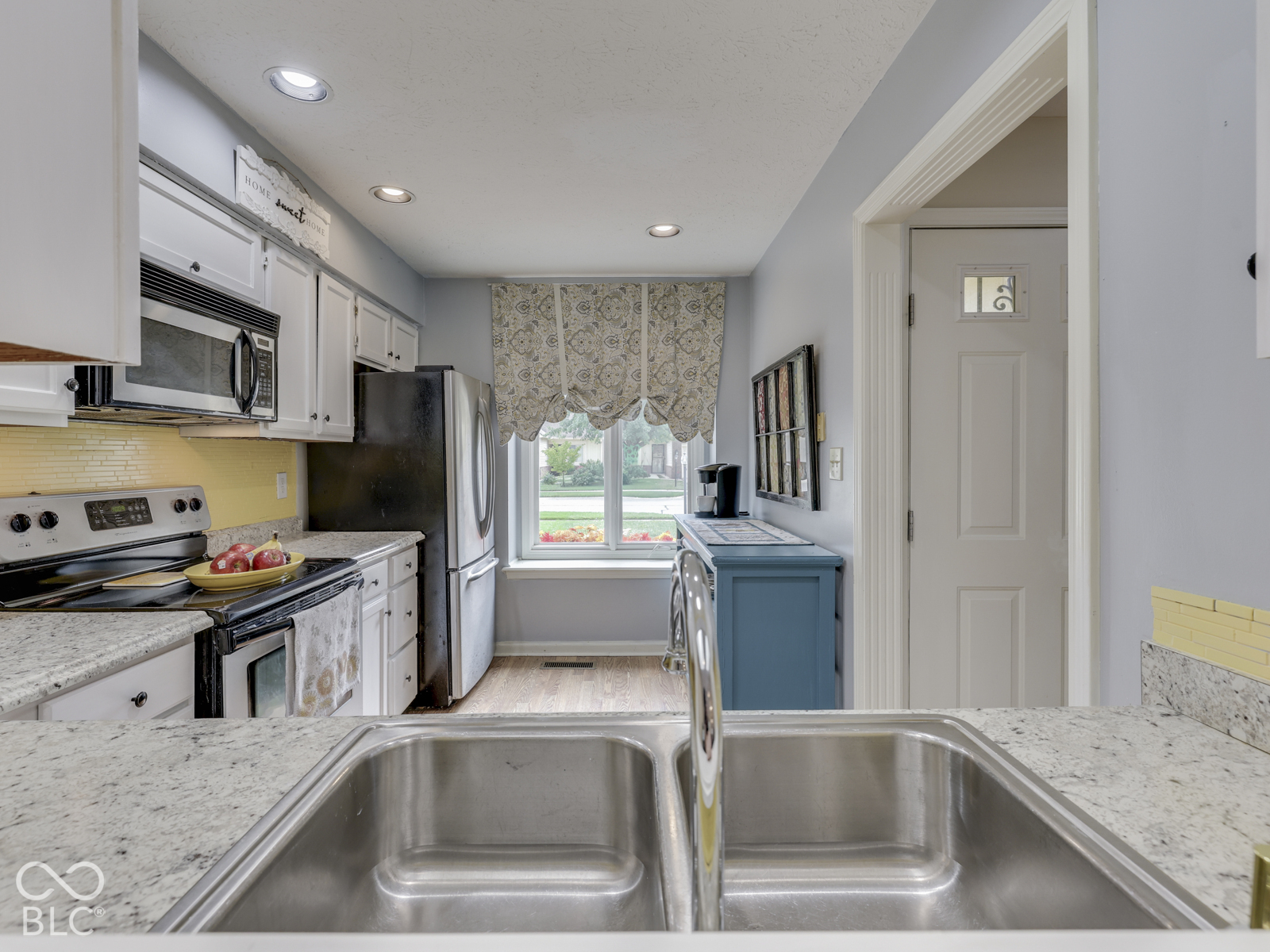 Kitchen featuring white cabinetry, stone-finish countertops, stainless steel dual-basin undermount sink, and recessed lighting